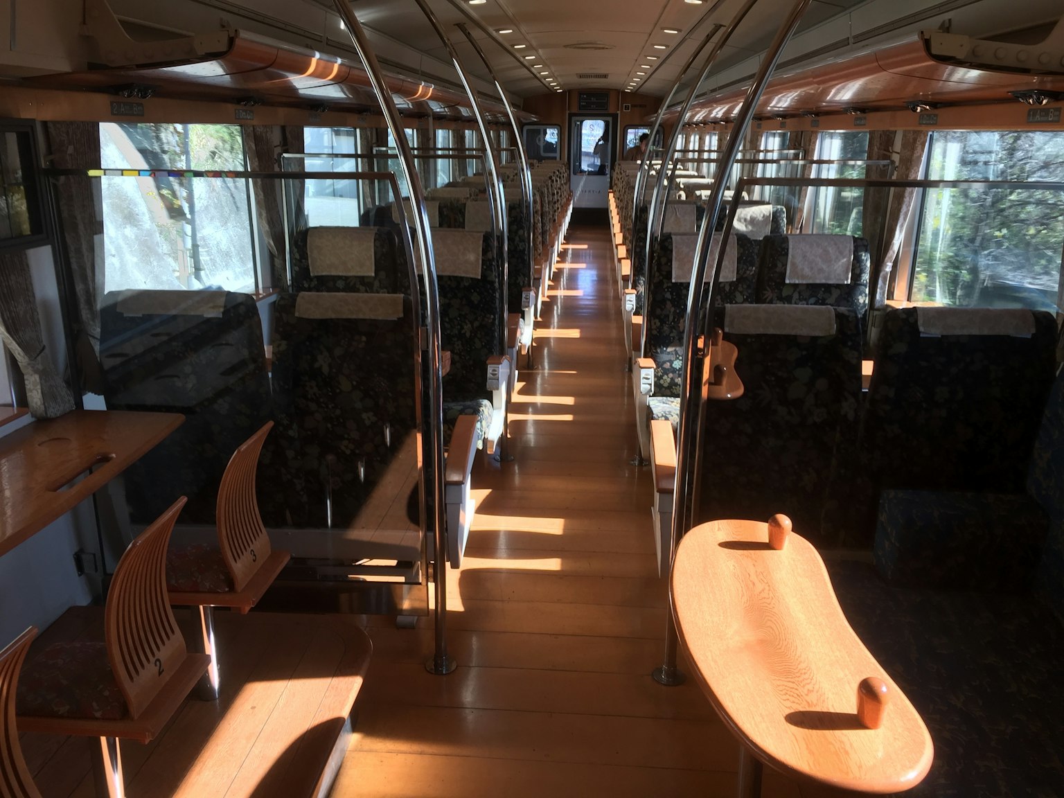 Interno luminoso di un treno con tavoli e sedie in legno