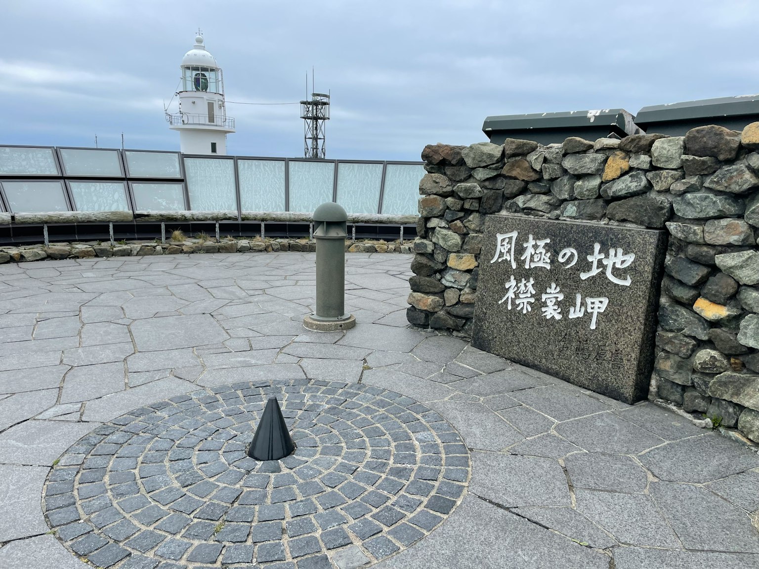 Landmark dengan monumen batu dan kerucut hitam di atas paving batu