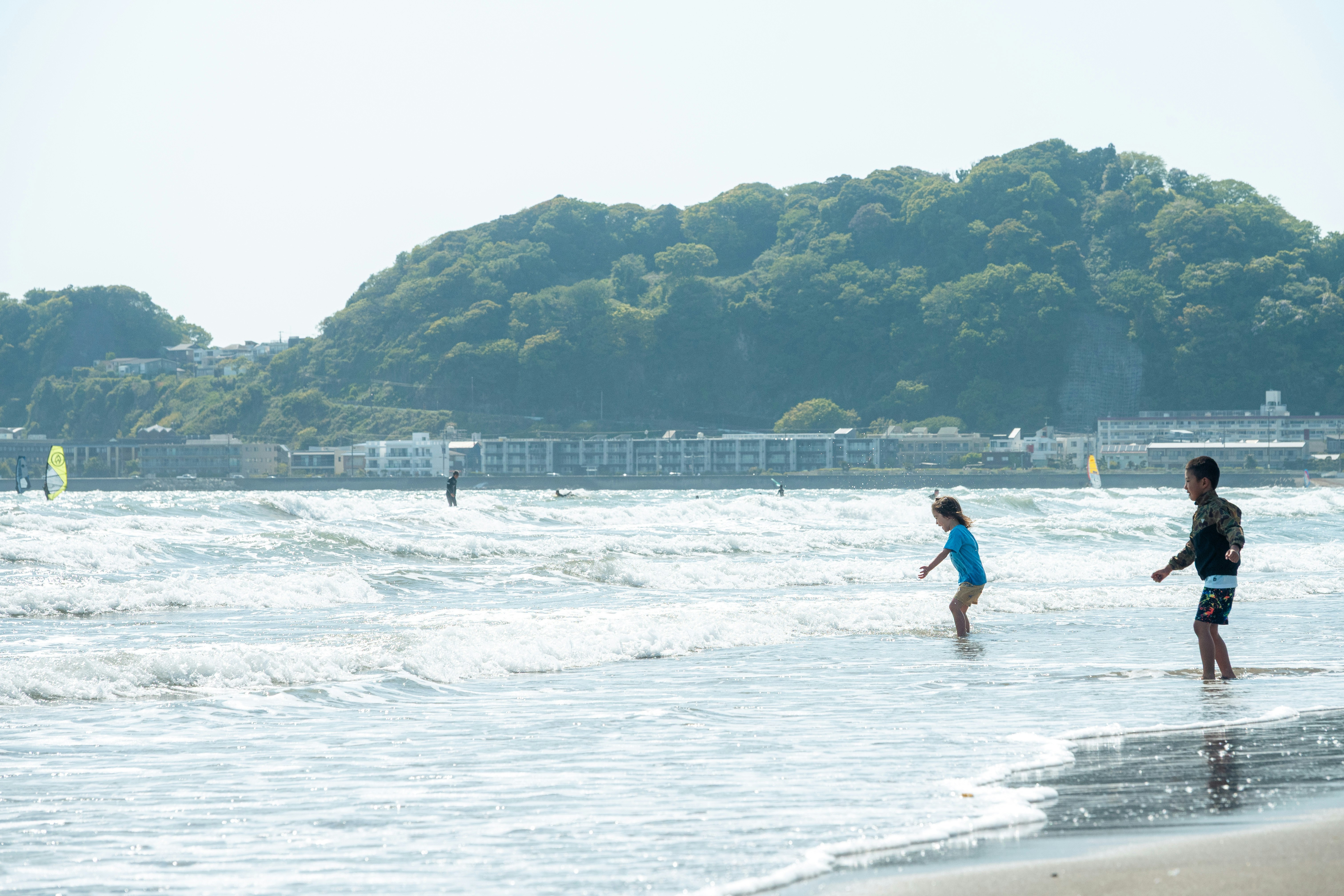 砂浜を走る子どもたちと穏やかな海の風景