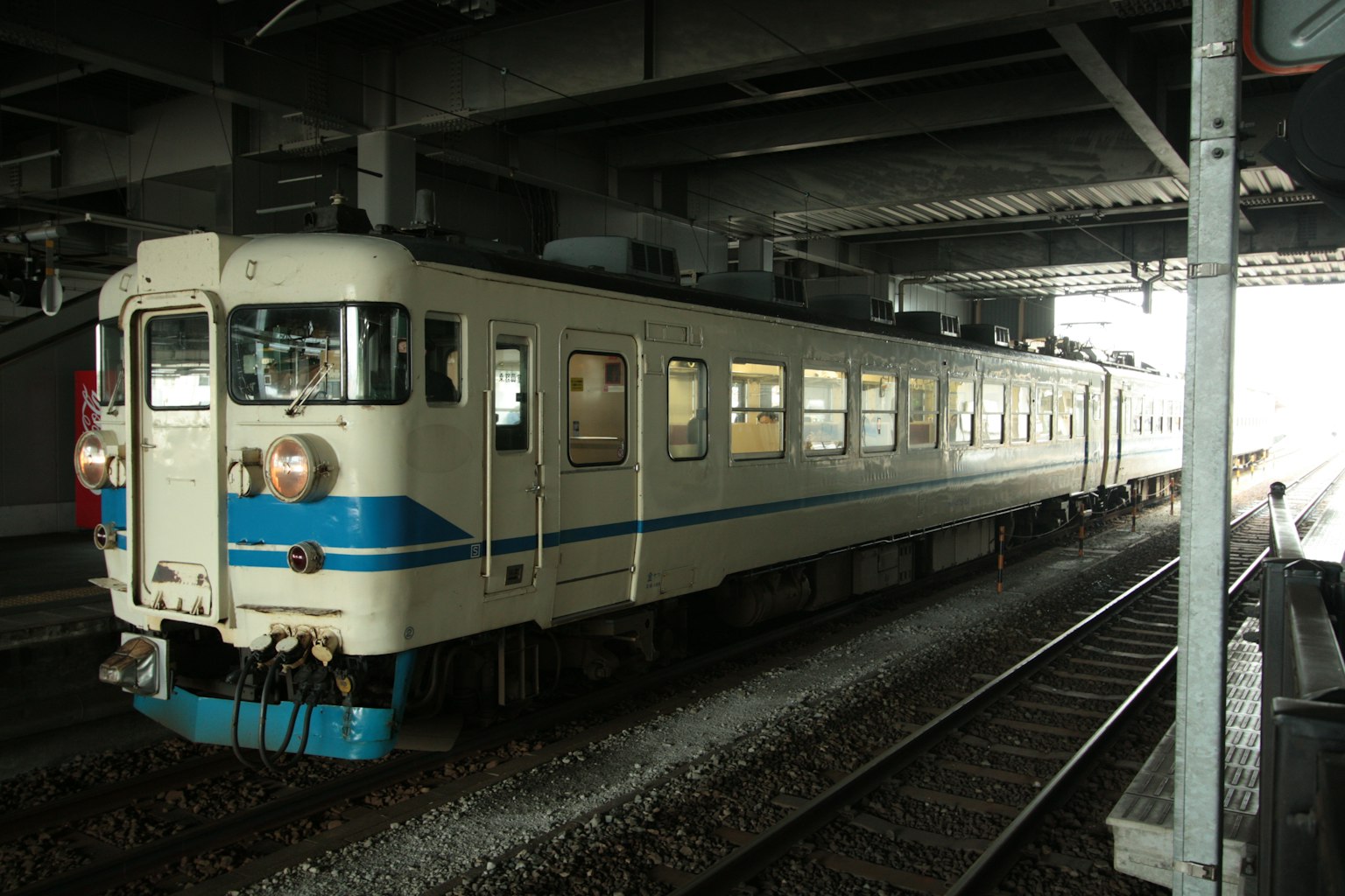 一列白色和藍色的火車停在車站屋頂下