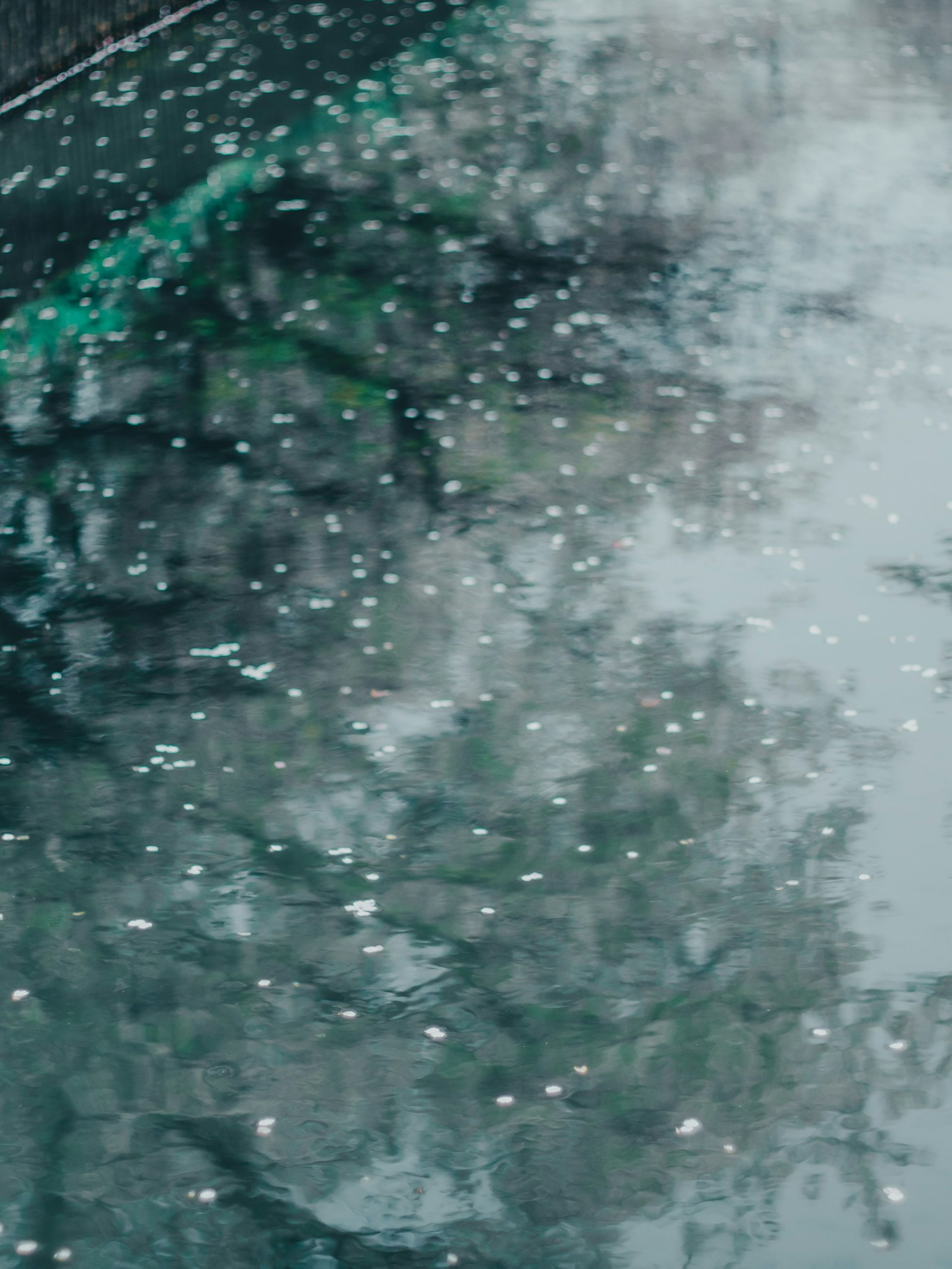 雨滴落在反射表面上，营造出宁静的氛围