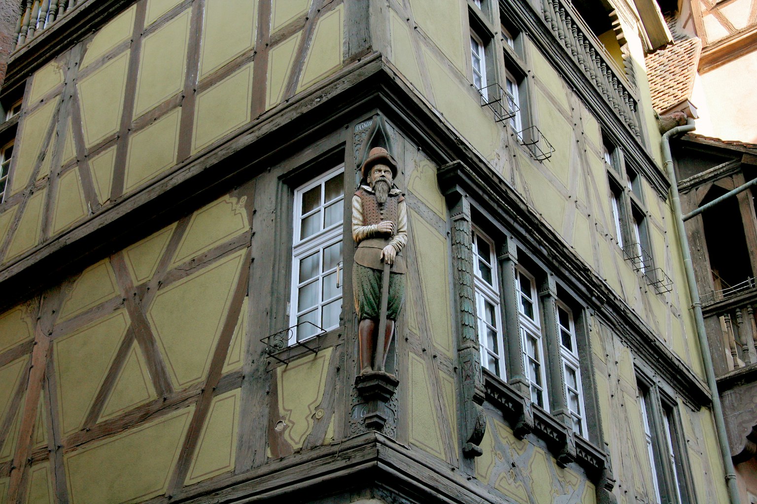 Scultura in legno di un uomo in piedi all'angolo di una casa