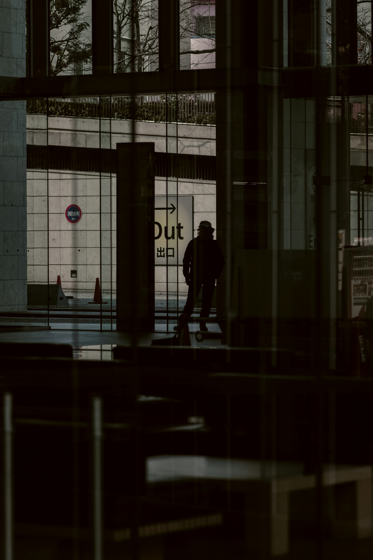 Silhouette di una persona che cammina all'interno di un edificio scuro con riflessi
