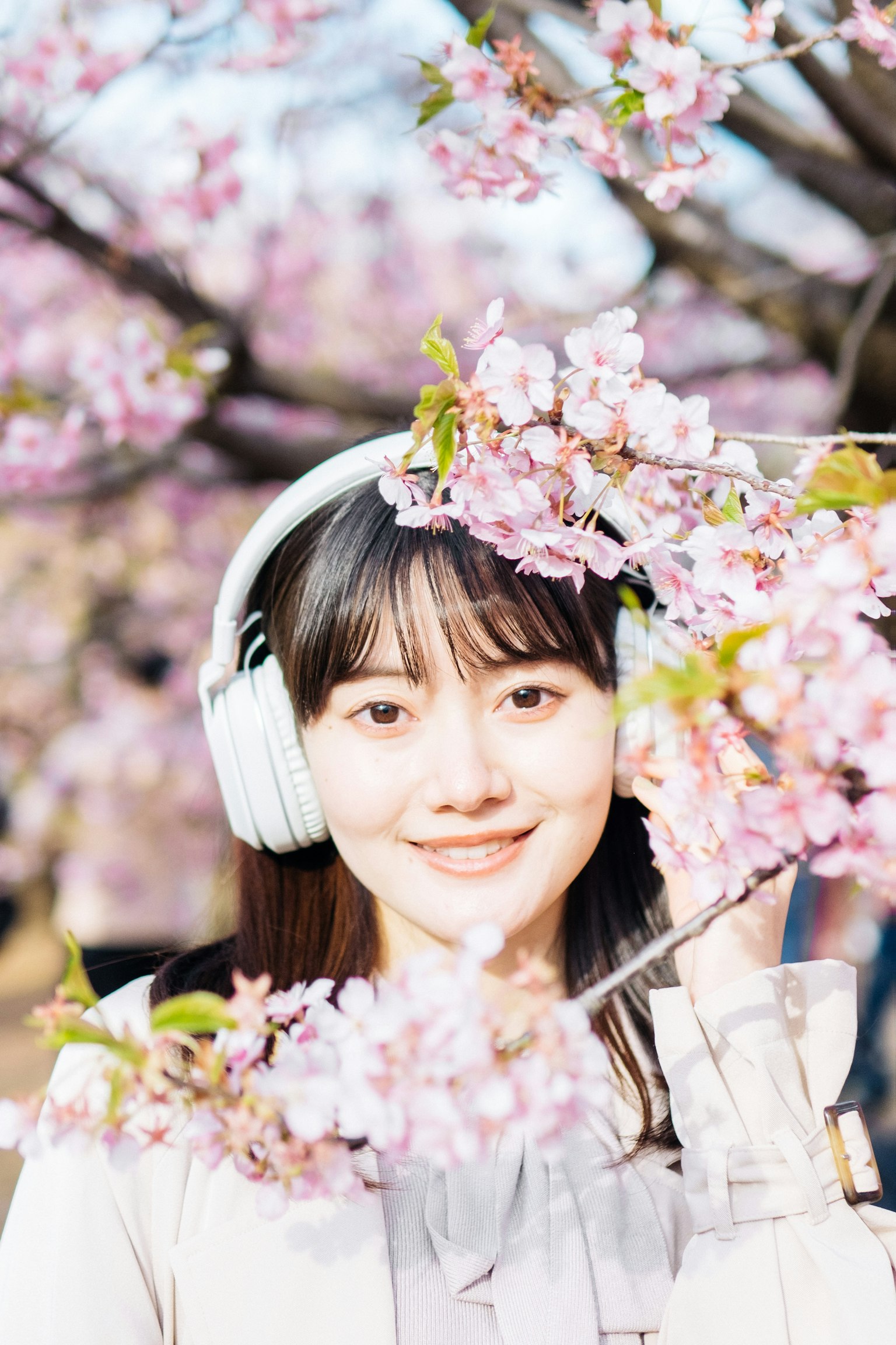 在樱花中微笑的女性戴着耳机