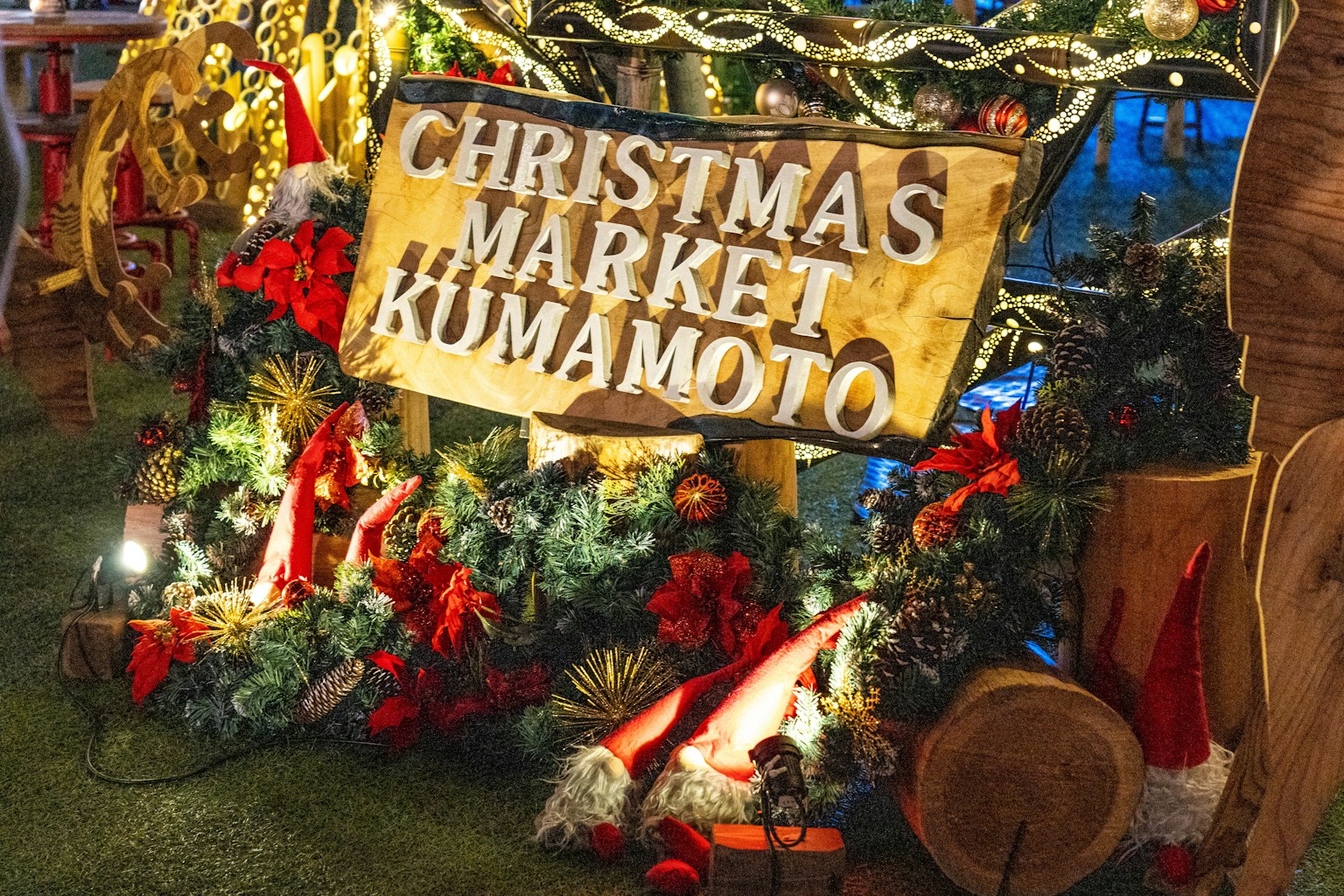 Cartel del Mercado de Navidad de Kumamoto rodeado de decoraciones festivas