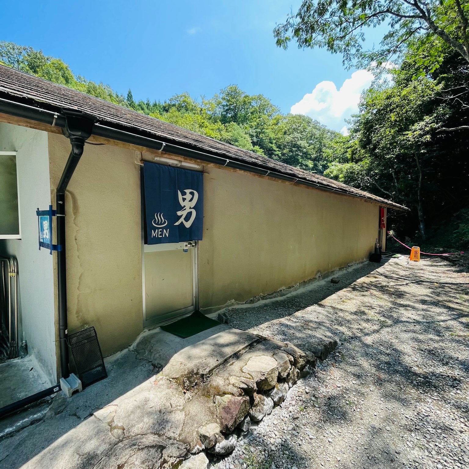 Exterior of a men's bathhouse in the mountains with blue sky