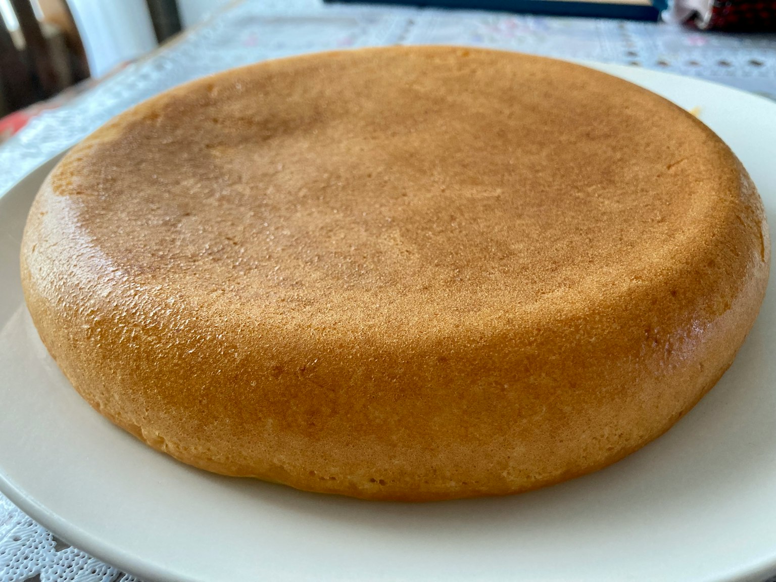 Ein flacher, glänzender brauner Kuchen auf einem weißen Teller