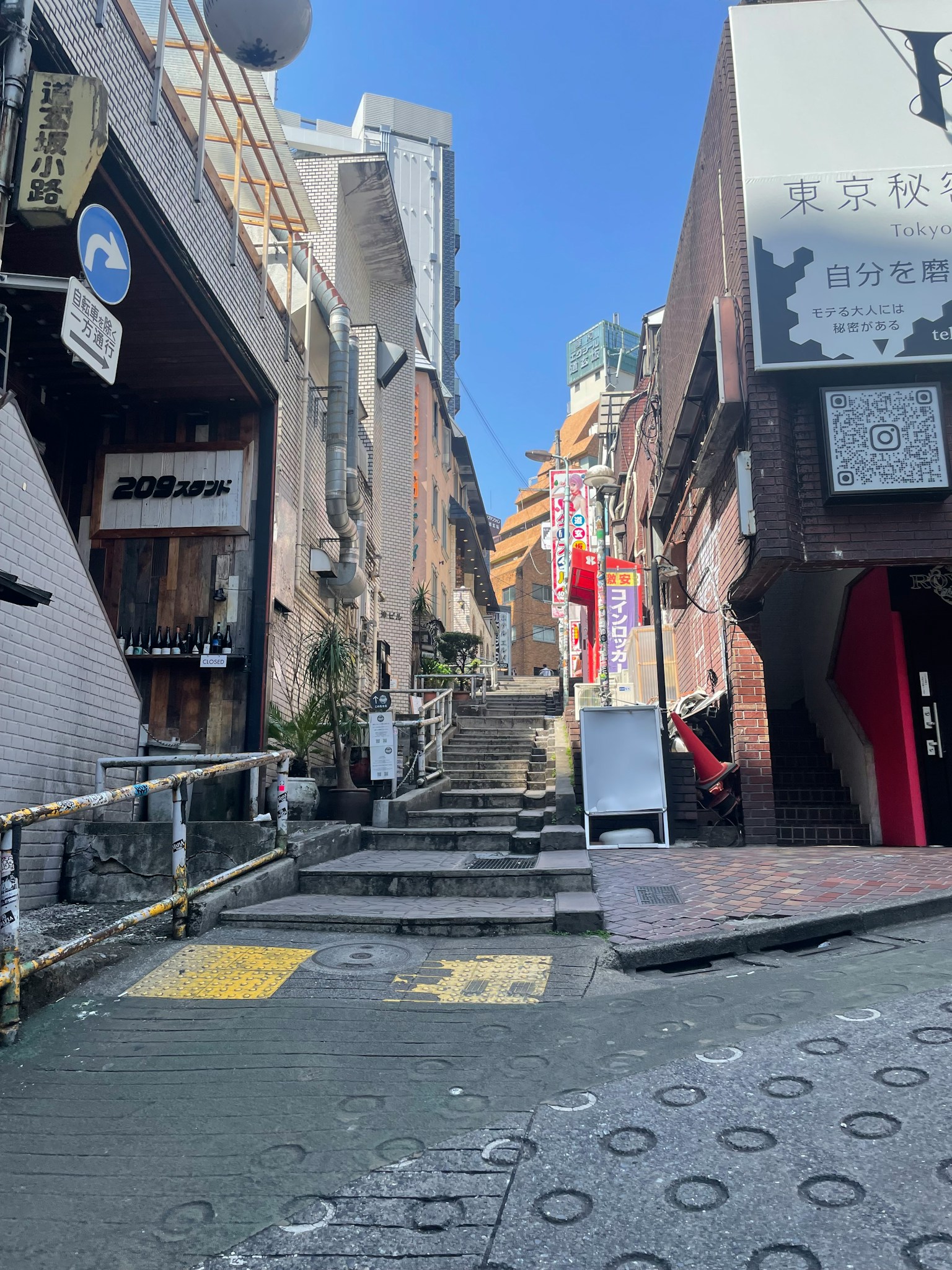 狭い通りと階段がある都市の風景 右側に看板と店舗が並ぶ