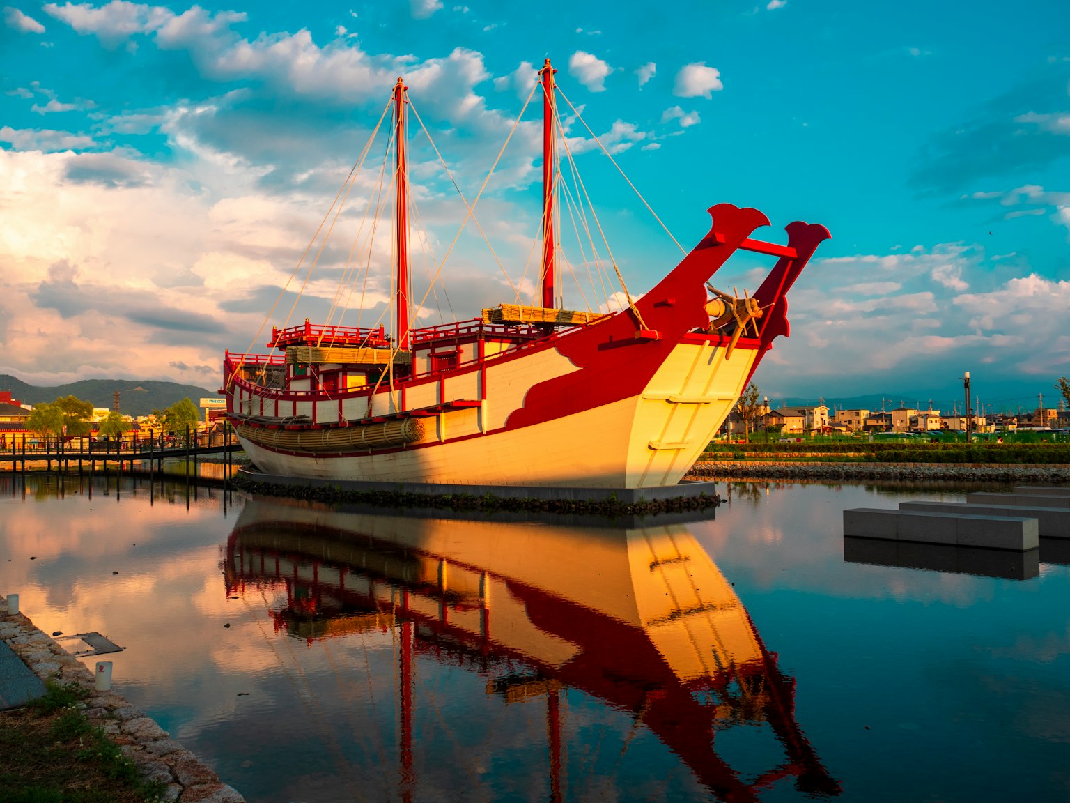 Traditionelles rotes und weißes Schiff spiegelt sich in ruhigem Wasser in einer malerischen Landschaft