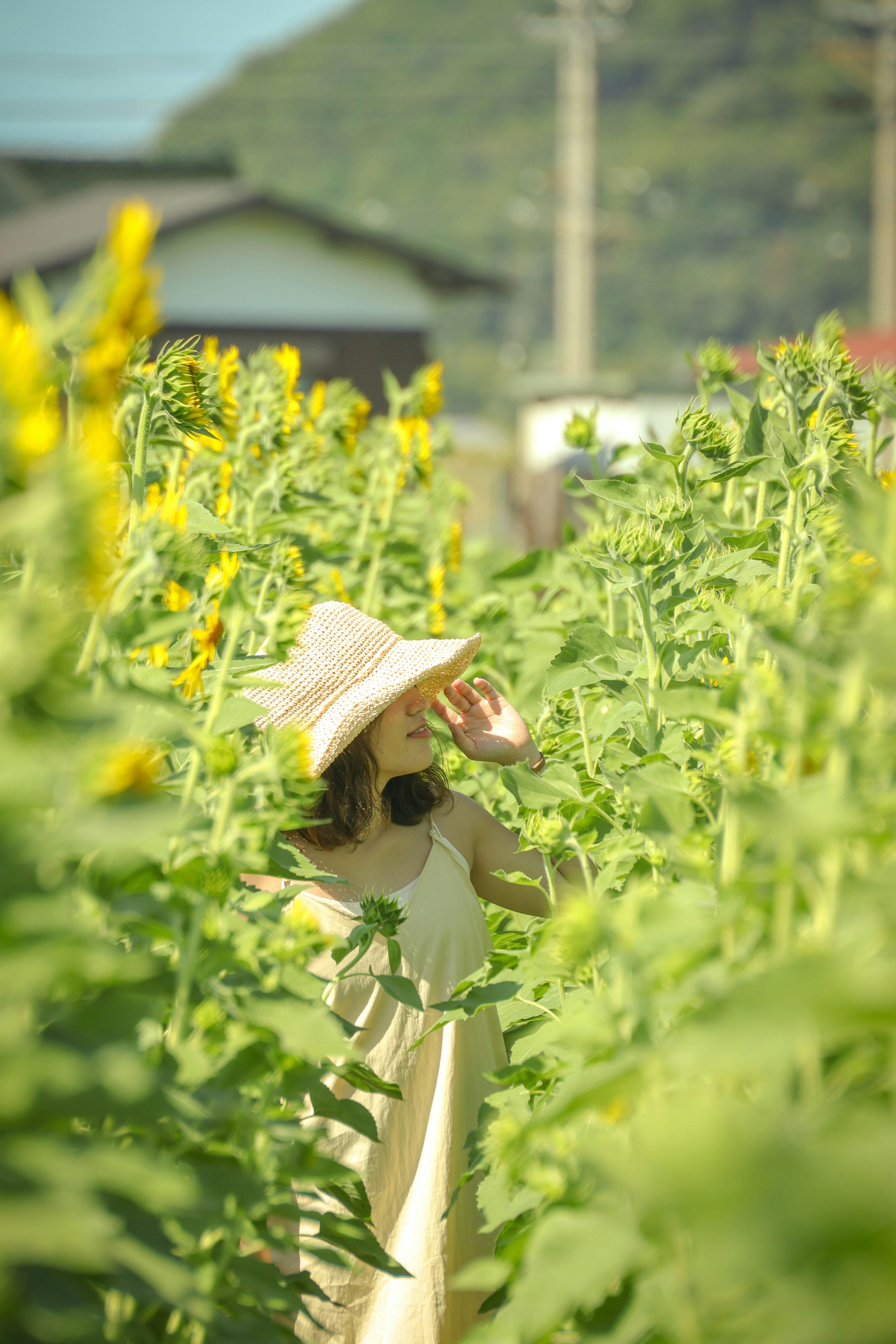 畑で麦わら帽子をかぶった親子が草花の間で過ごす風景