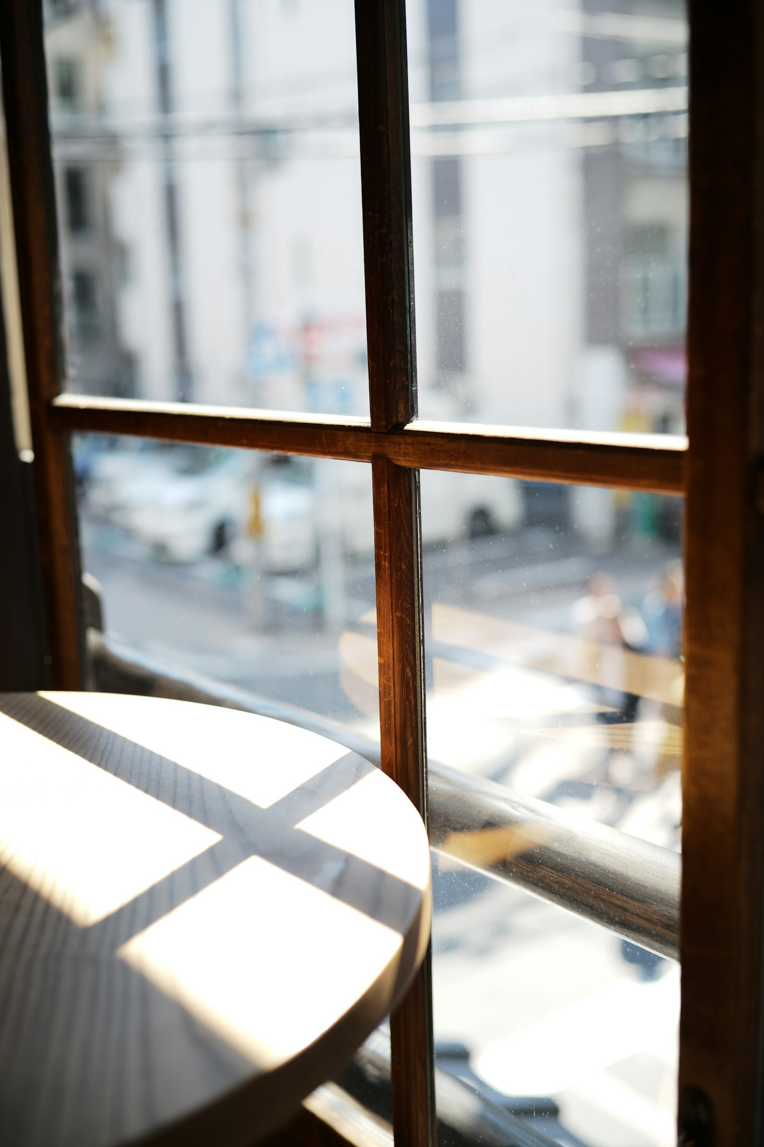 Vista de una calle a través de una ventana brillante con una mesa de madera