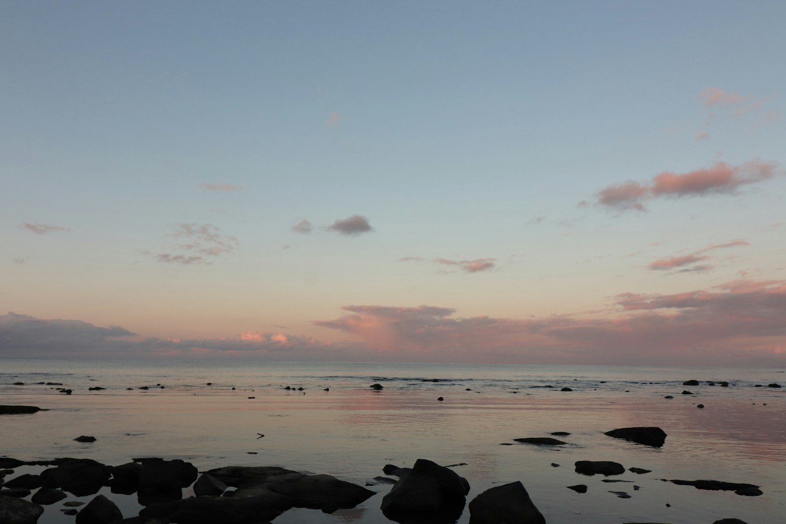 Vista panoramica dell'oceano al tramonto con acqua vibrante e rocce visibili