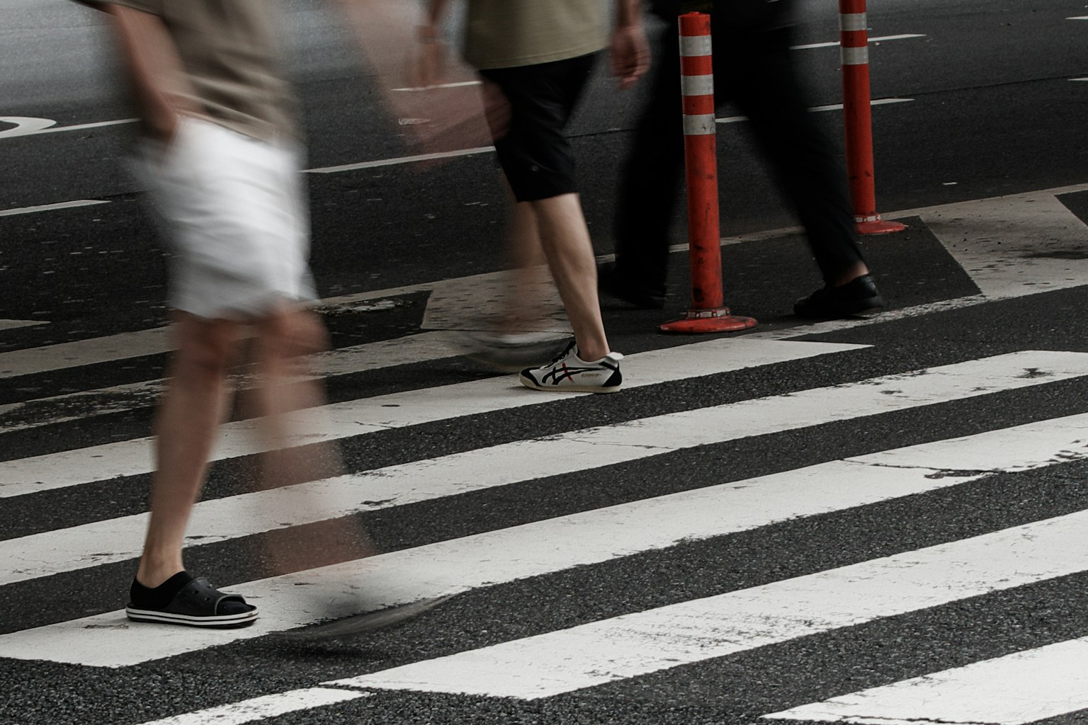 People walking on a crosswalk wearing shorts and sneakers