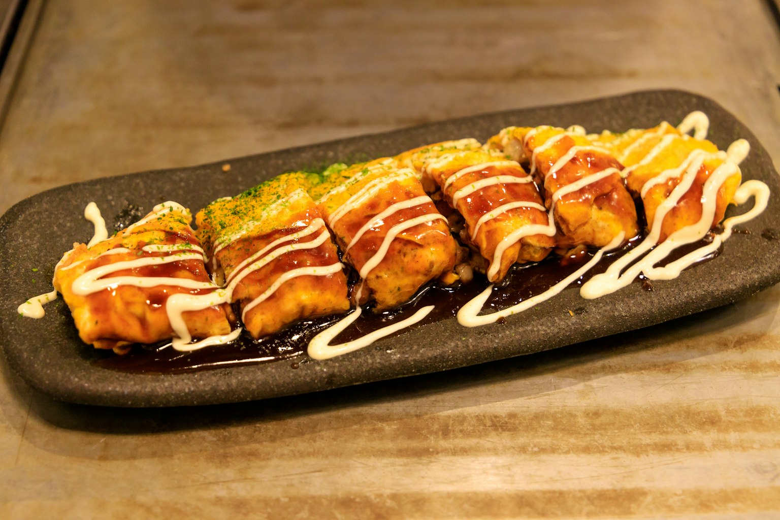 Sushi grillé présenté sur une assiette noire