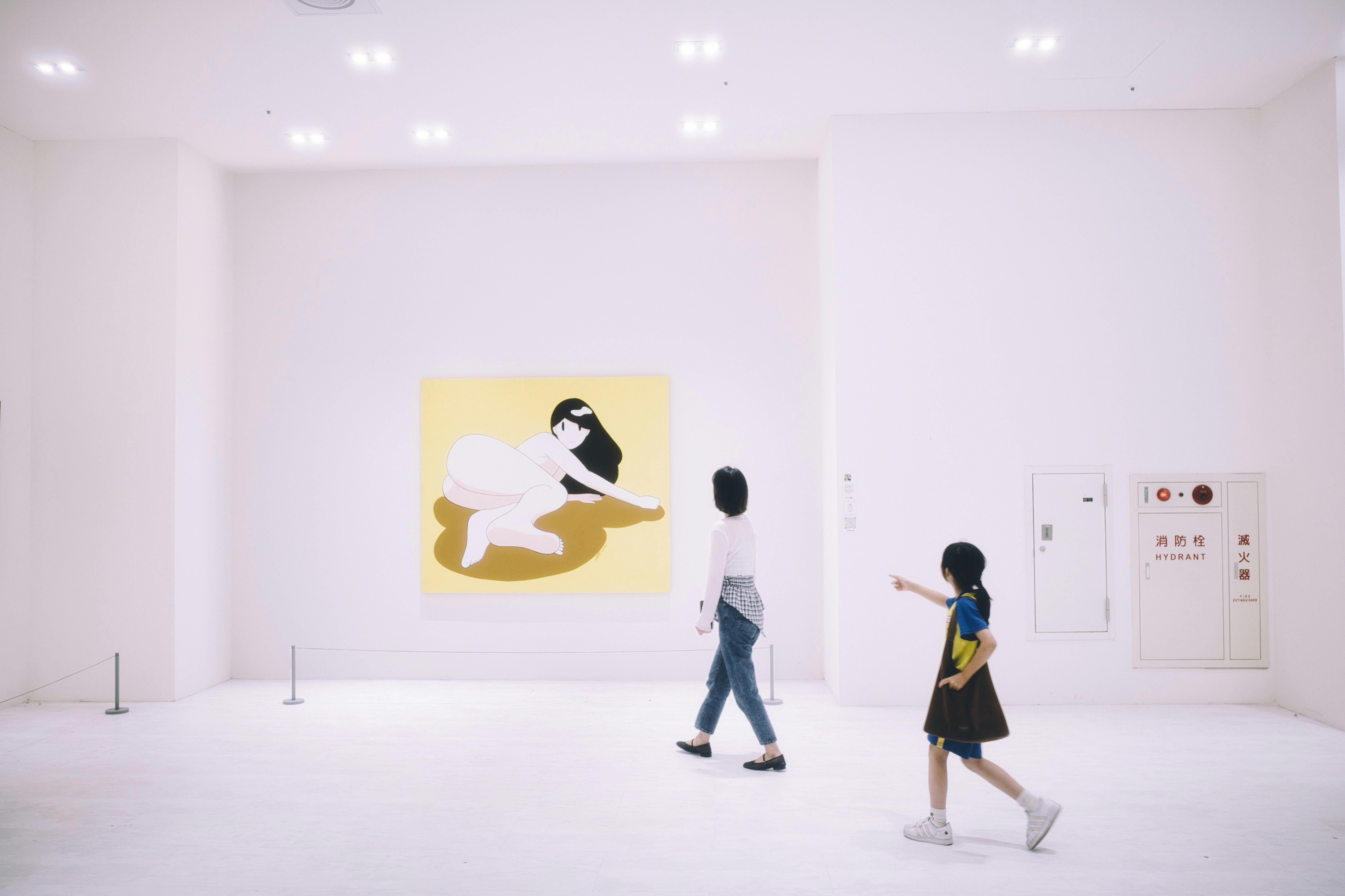 白い展示空間で歩く来場者と壁面アート