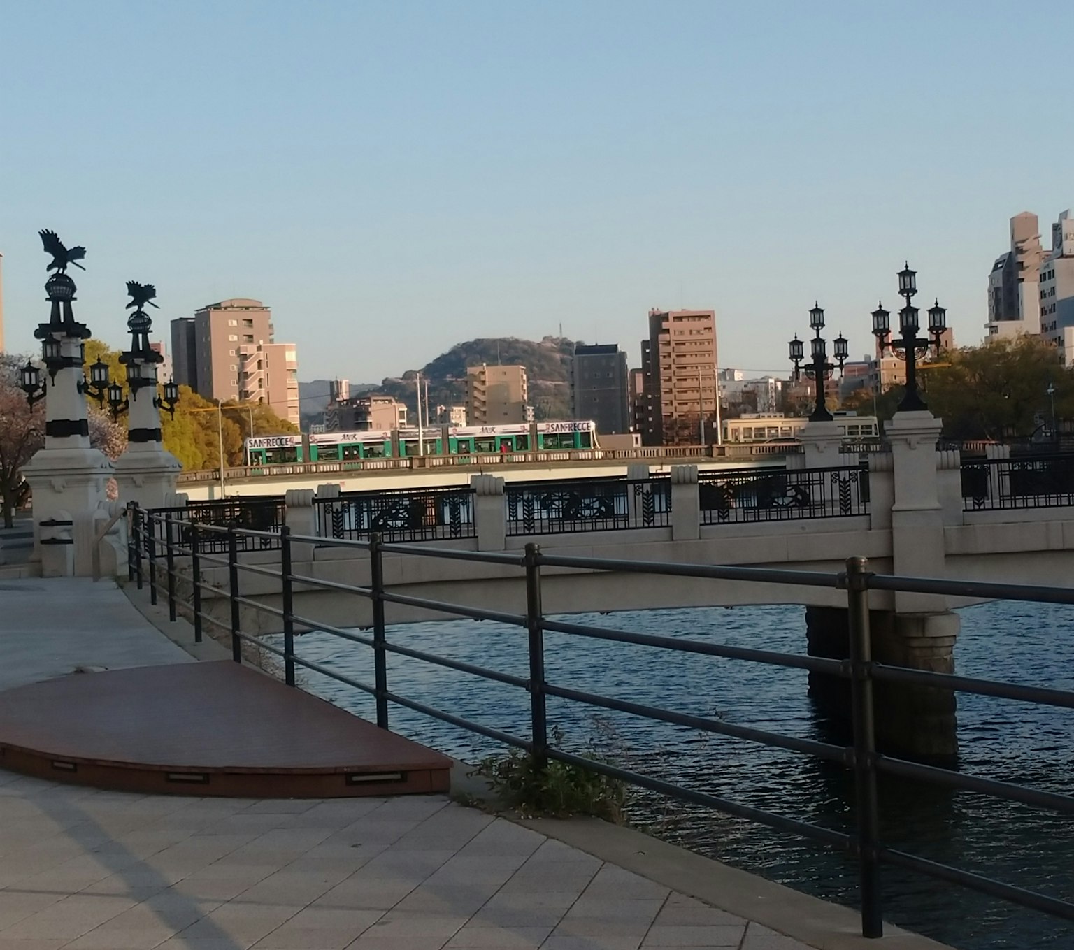 河边风景，背景有建筑物和带火车的桥