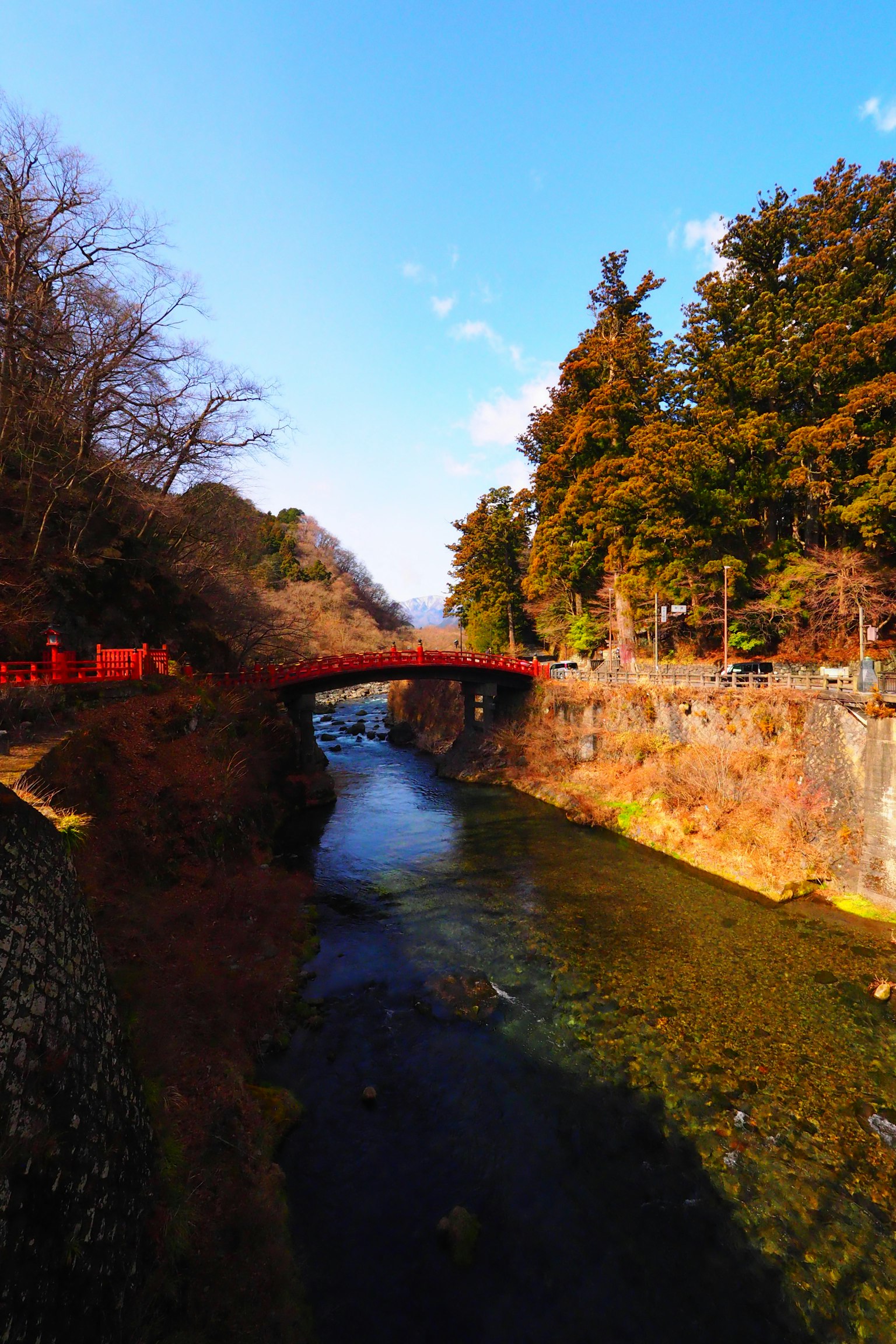 ทิวทัศน์ที่สวยงามของสะพานแดงเหนือแม่น้ำใสที่มีต้นไม้ล้อมรอบ