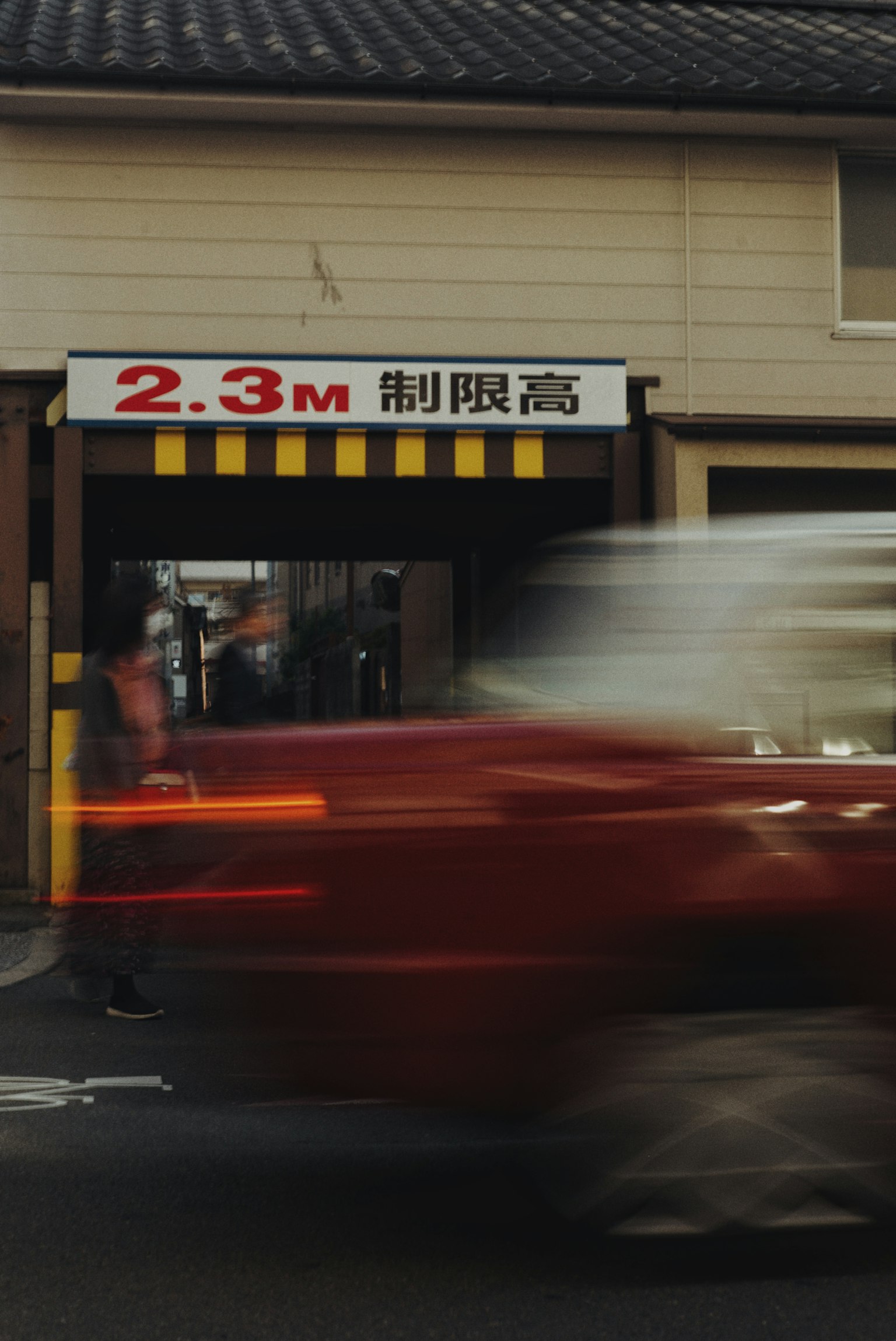 Cổng vào của tòa nhà thương mại với biển báo giới hạn chiều cao 2,3 mét xe đỏ đi qua