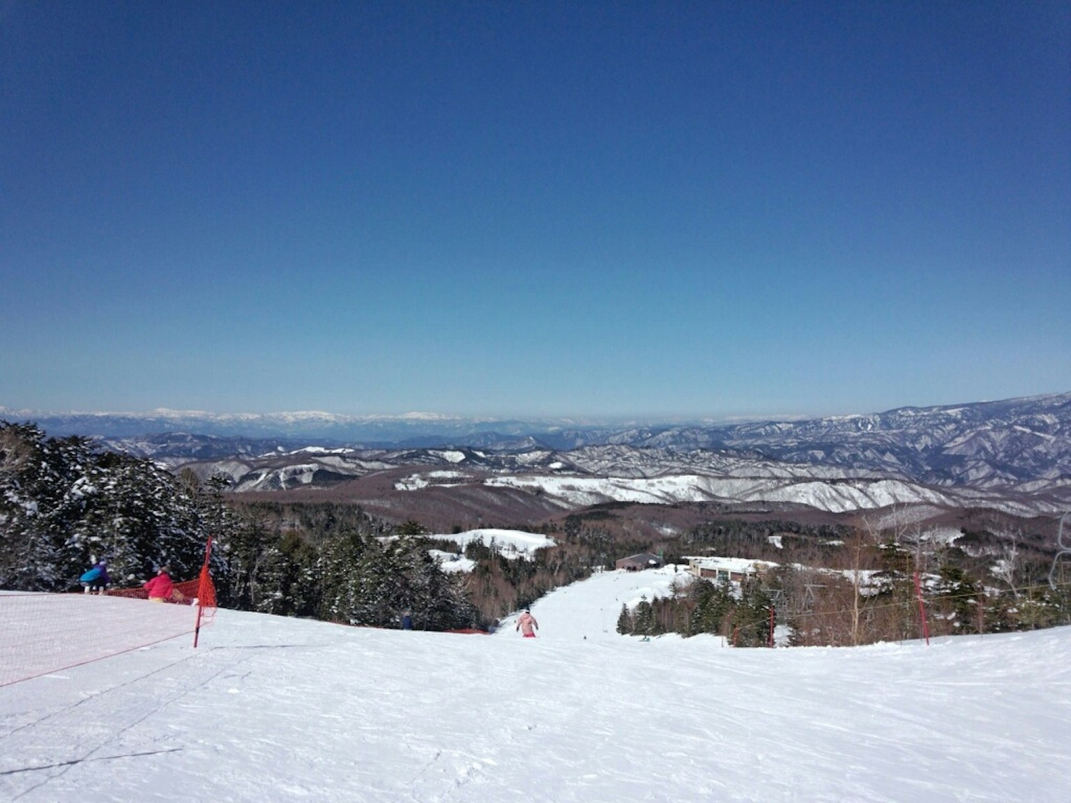 Snow-covered mountain slope view with blue sky and distant mountains