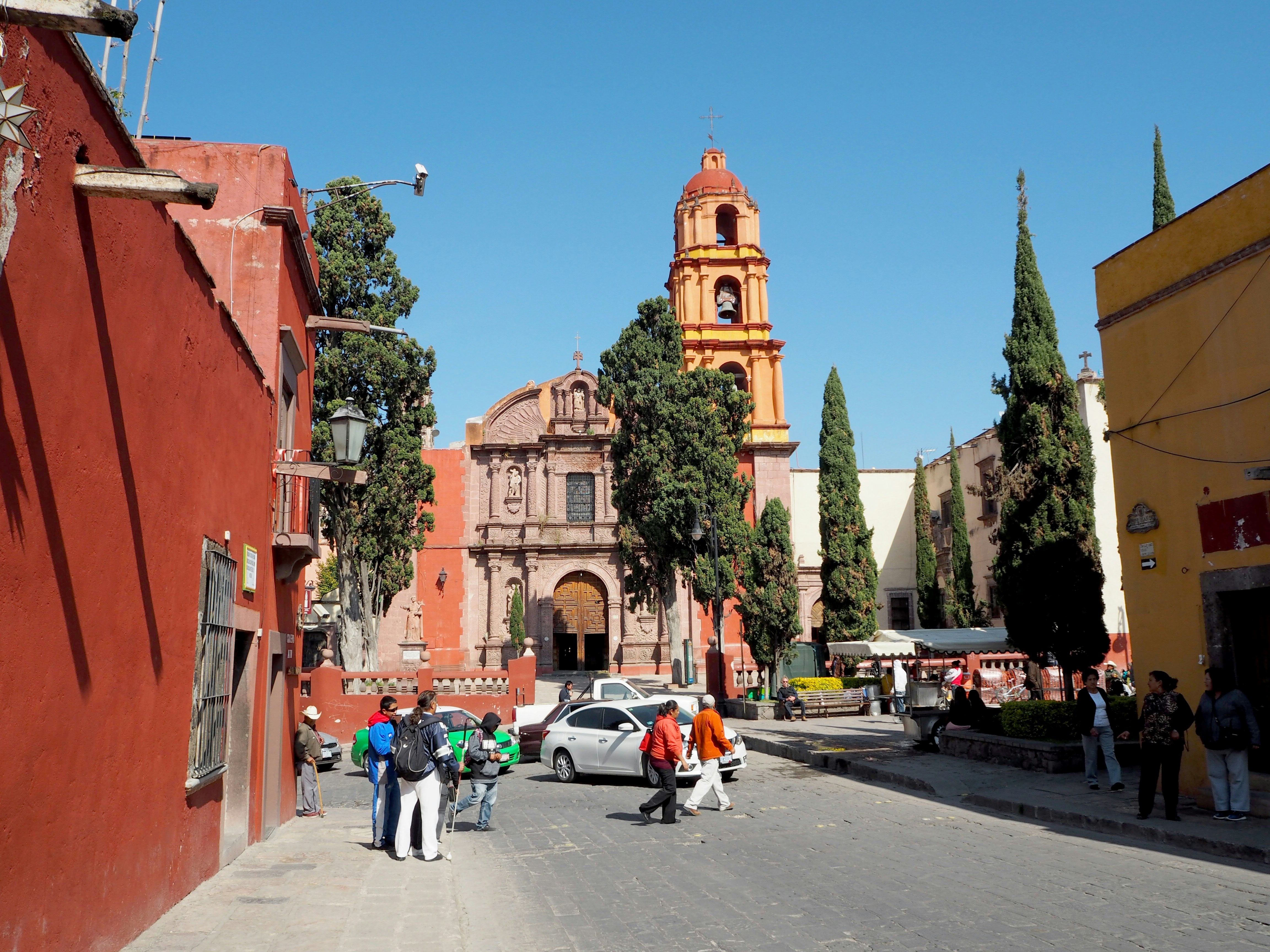 メキシコの街角の風景で赤い建物とオレンジ色の教会が見える