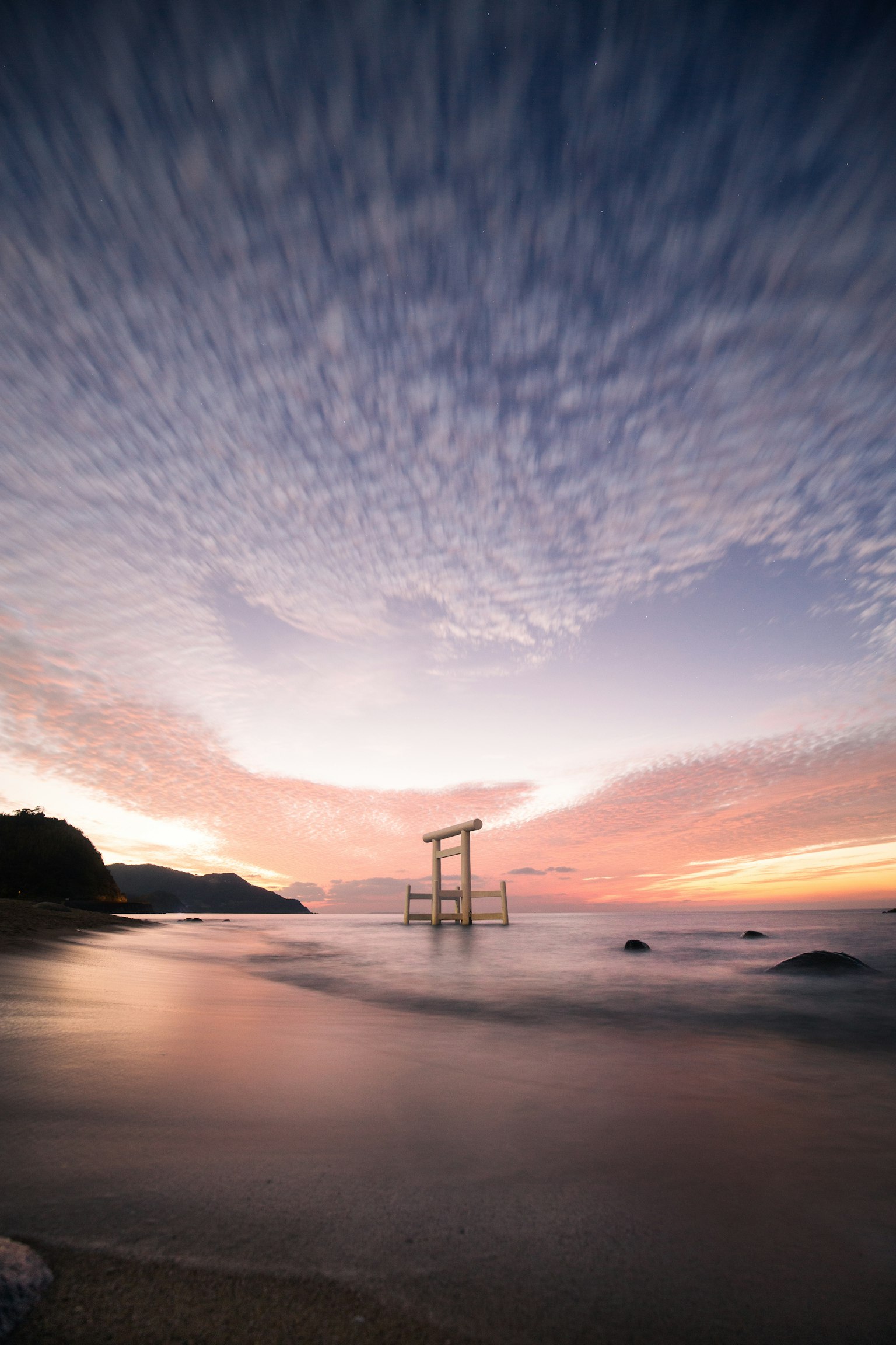 Torii gate by the seaside under a beautiful sunset sky