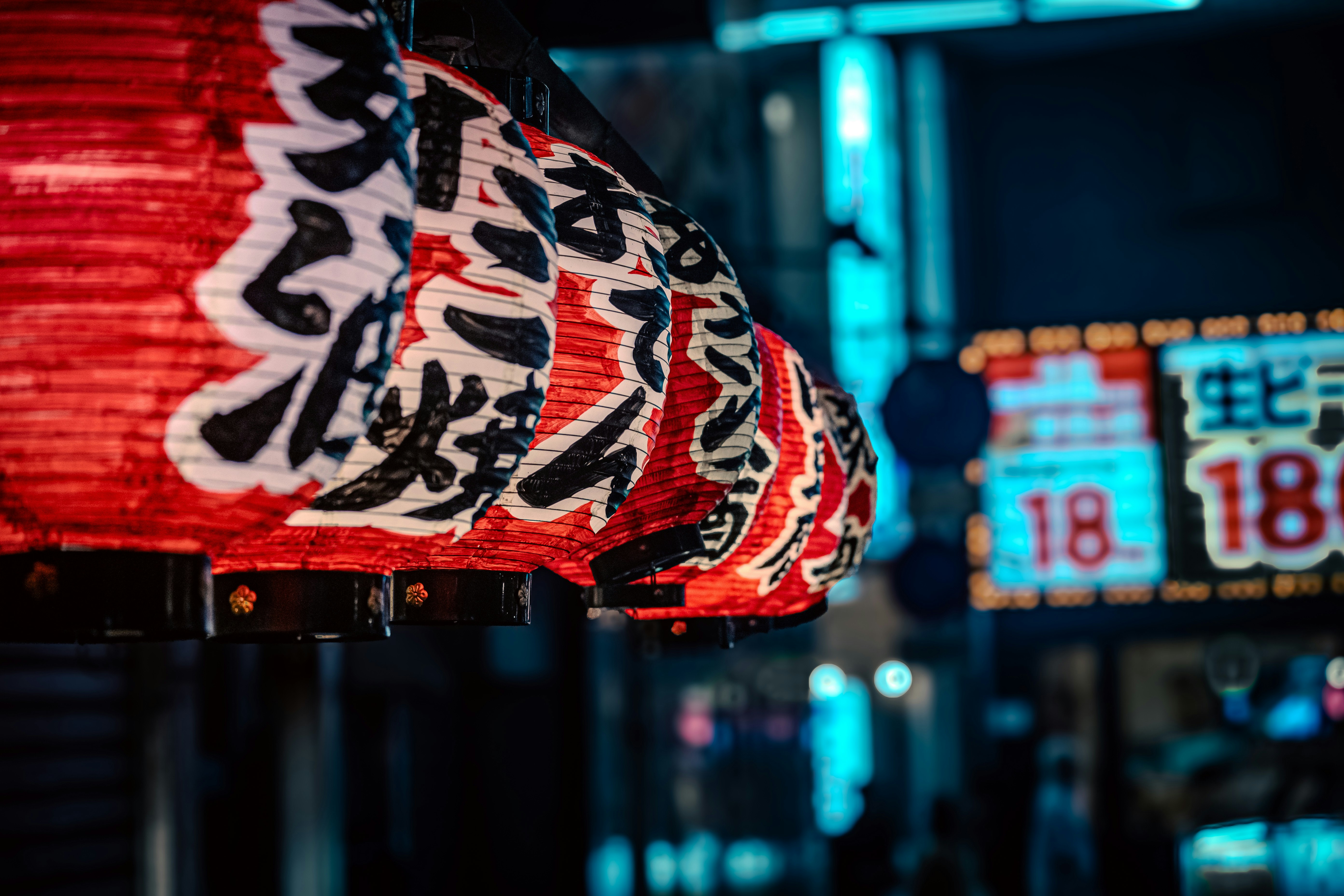 Red lantern glow reflecting on a street stall sign and neon lights