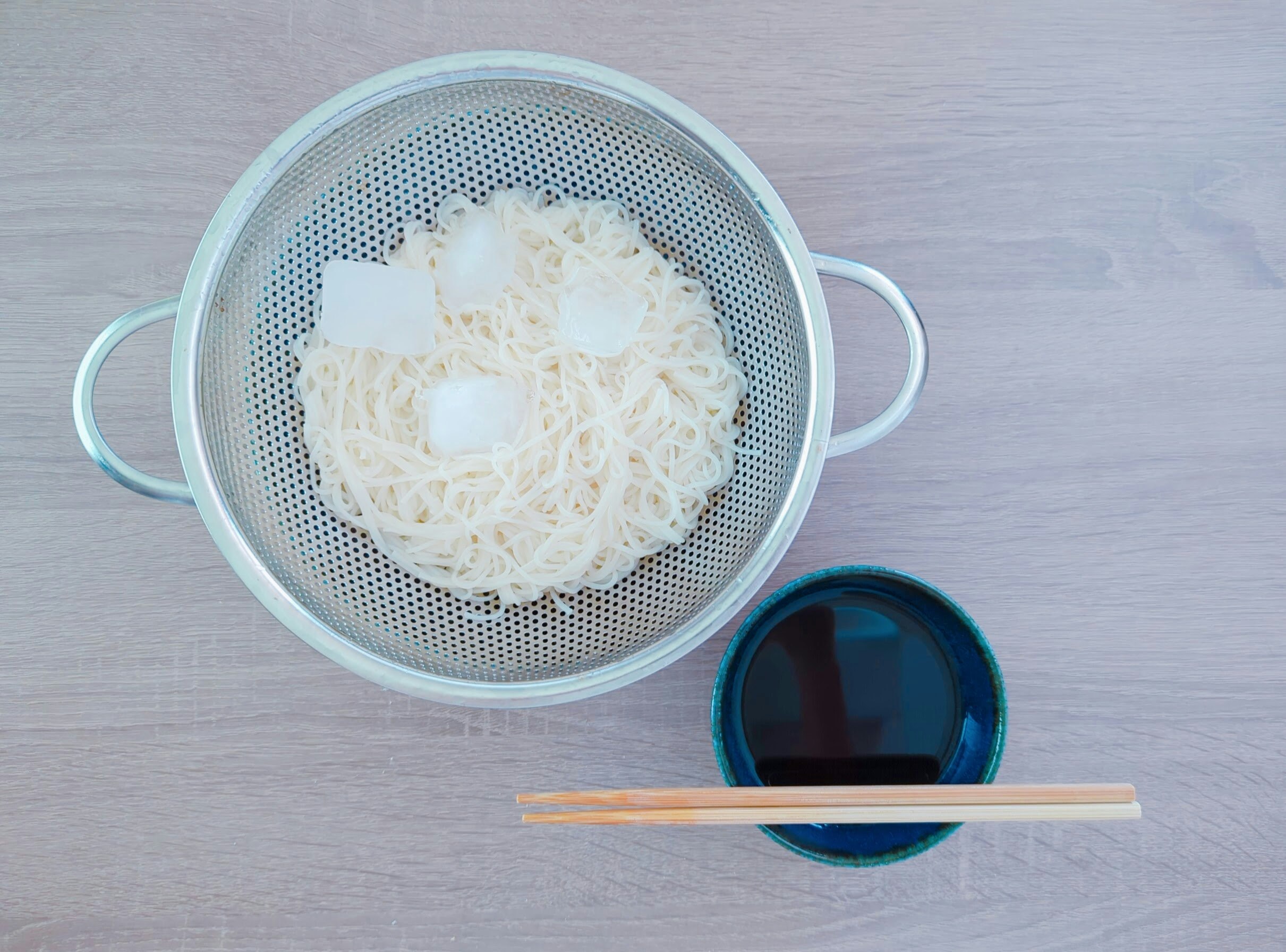 draining strainer with white noodles and chopsticks