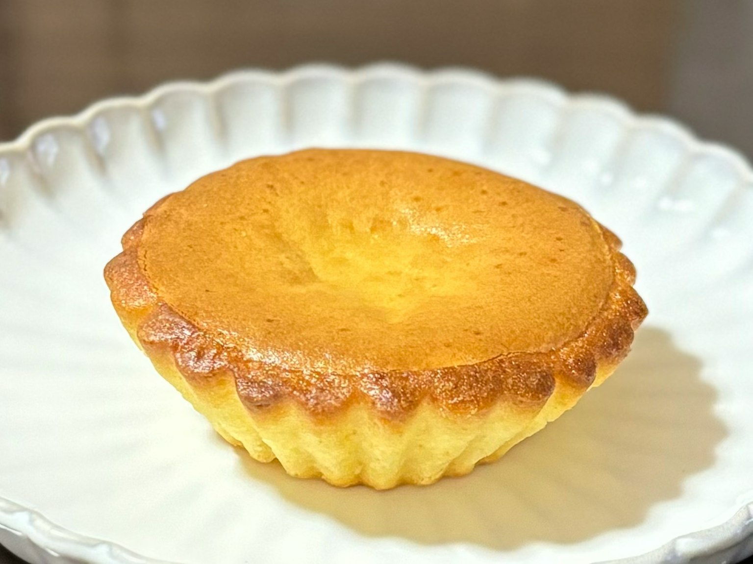A golden brown cupcake sits on a white plate