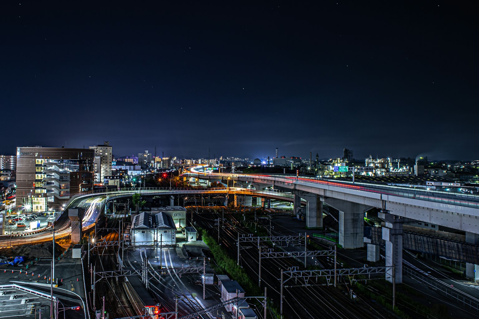 Paesaggio urbano notturno con ferrovie e strade sopraelevate illuminate dalle luci della città