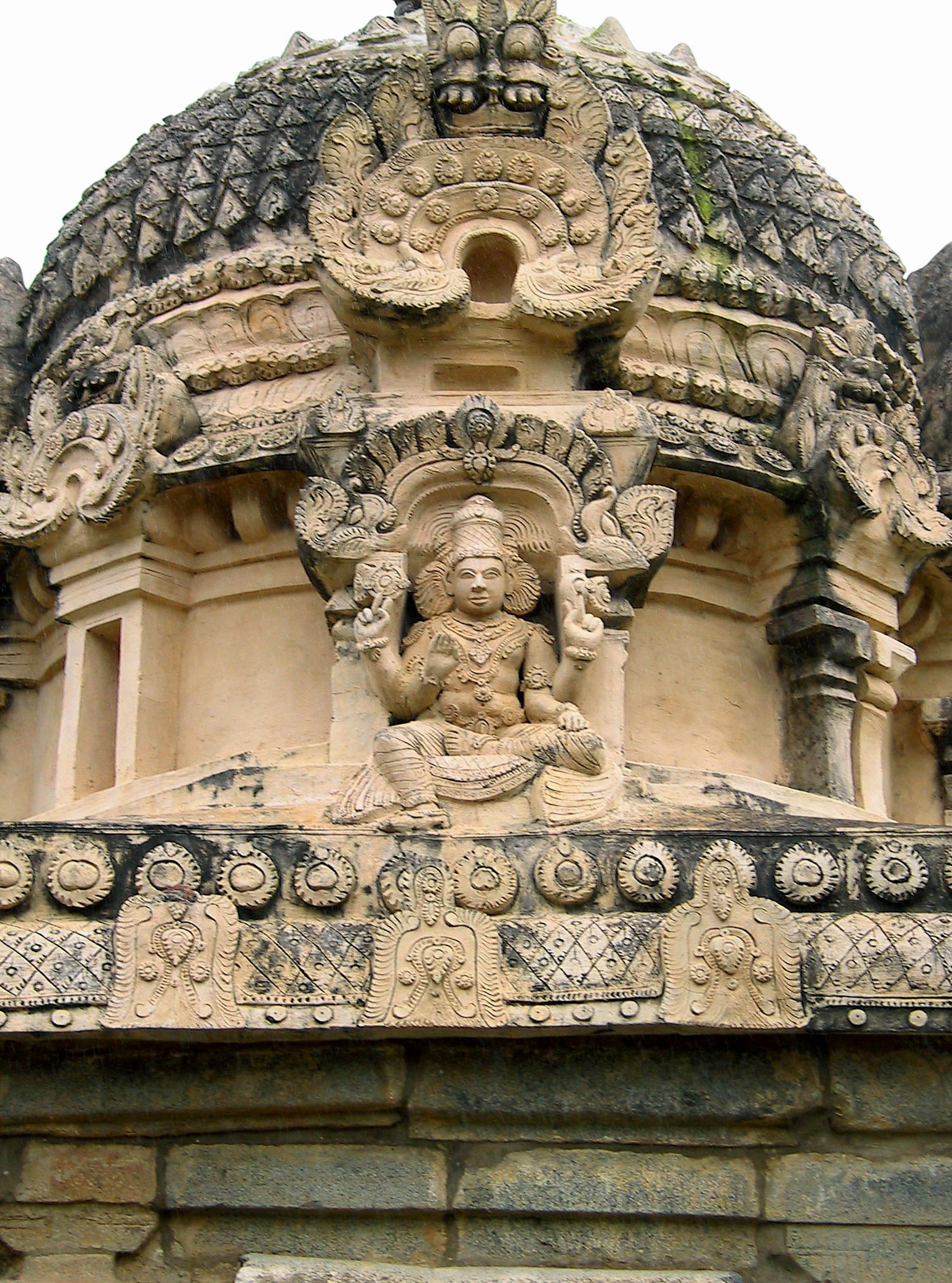 Cúpula de un templo antiguo con intrincados tallados y una estatua central rodeada de elementos decorativos