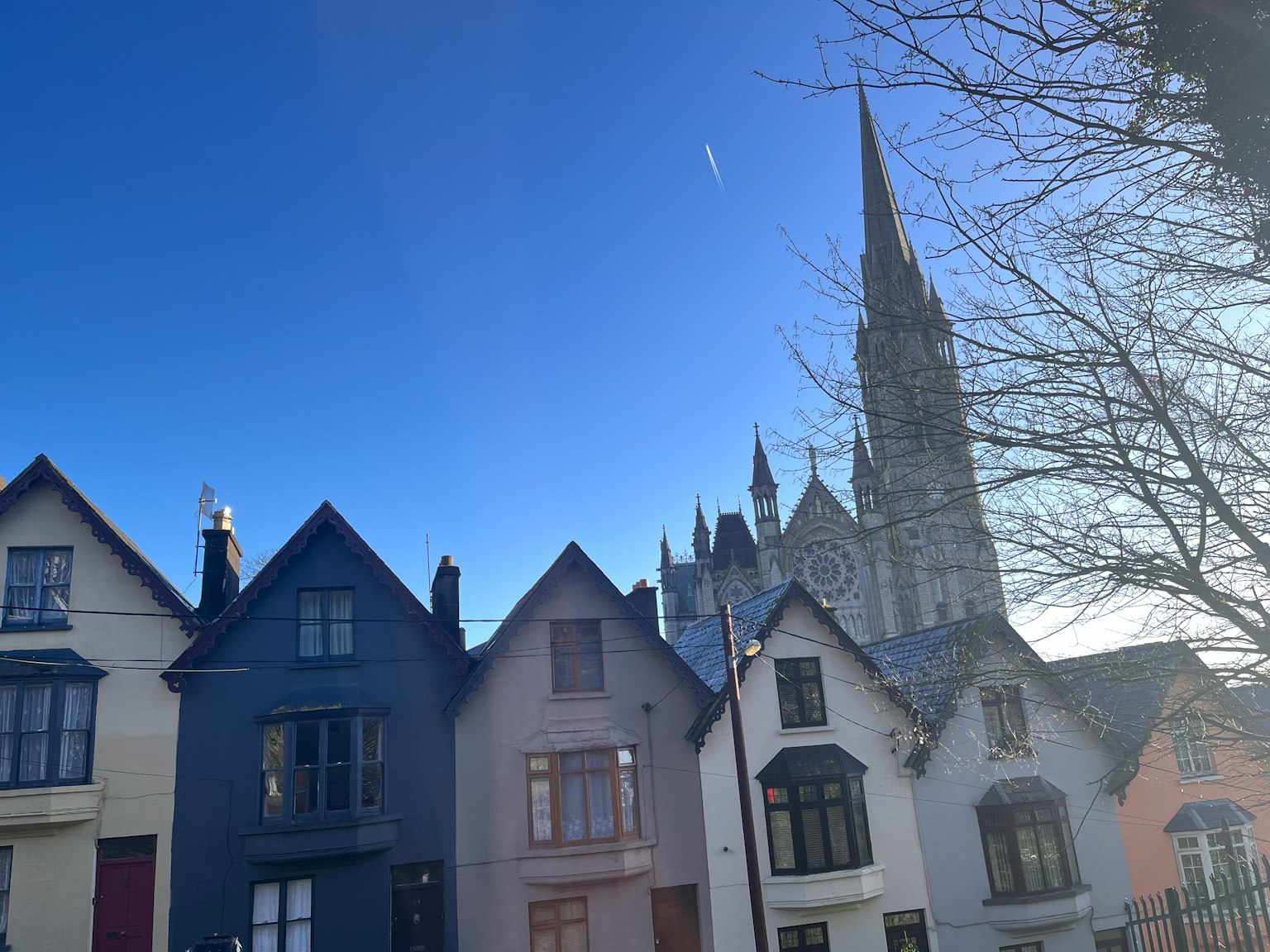 Colorful houses under a clear blue sky with a cathedral spire in the background