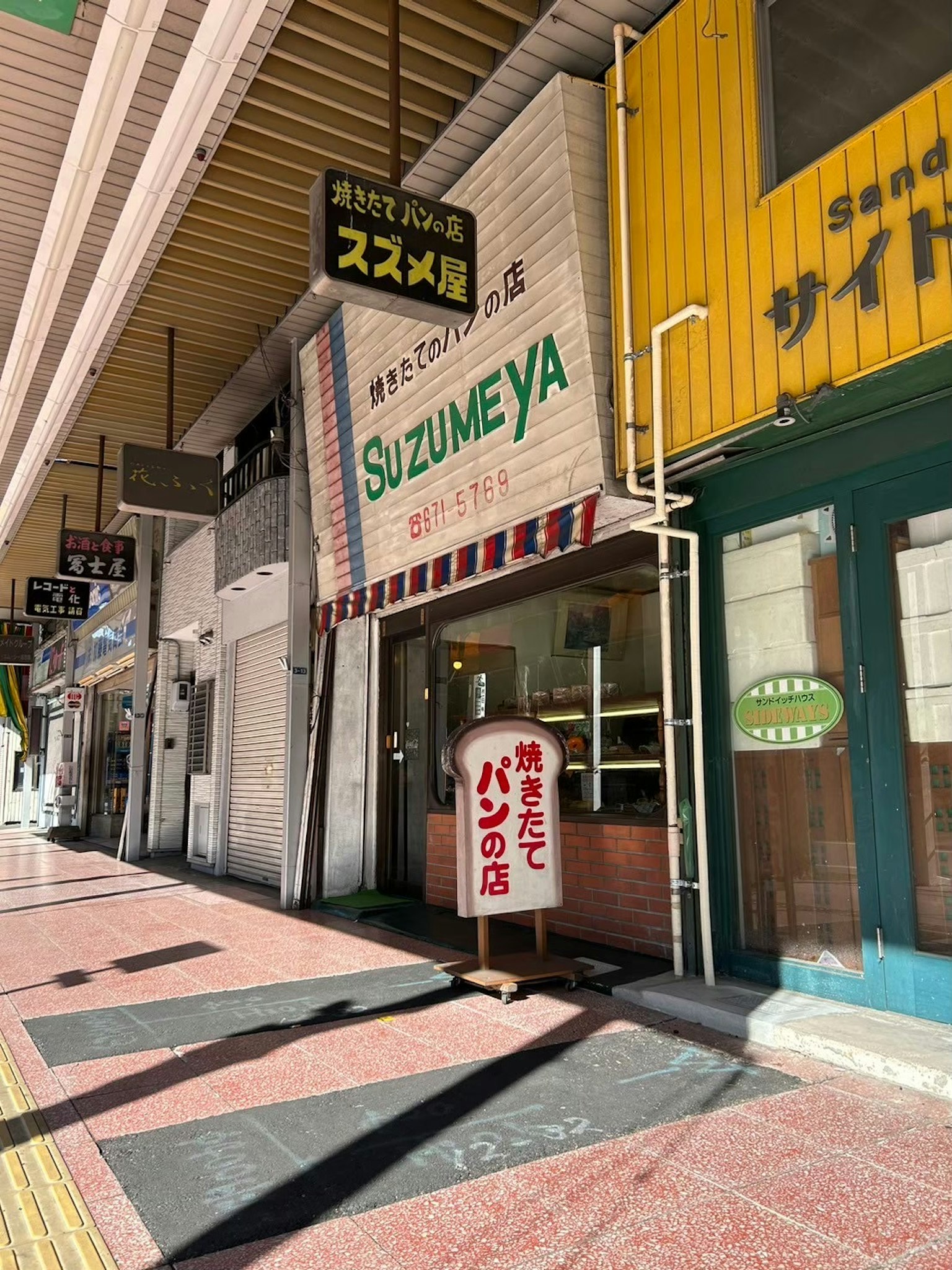 Extérieur d'un magasin avec une enseigne Suzumeya dans une arcade commerçante