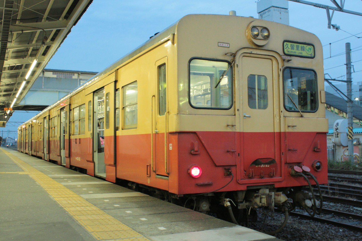 Orange and cream-colored train stopped at a station during dusk