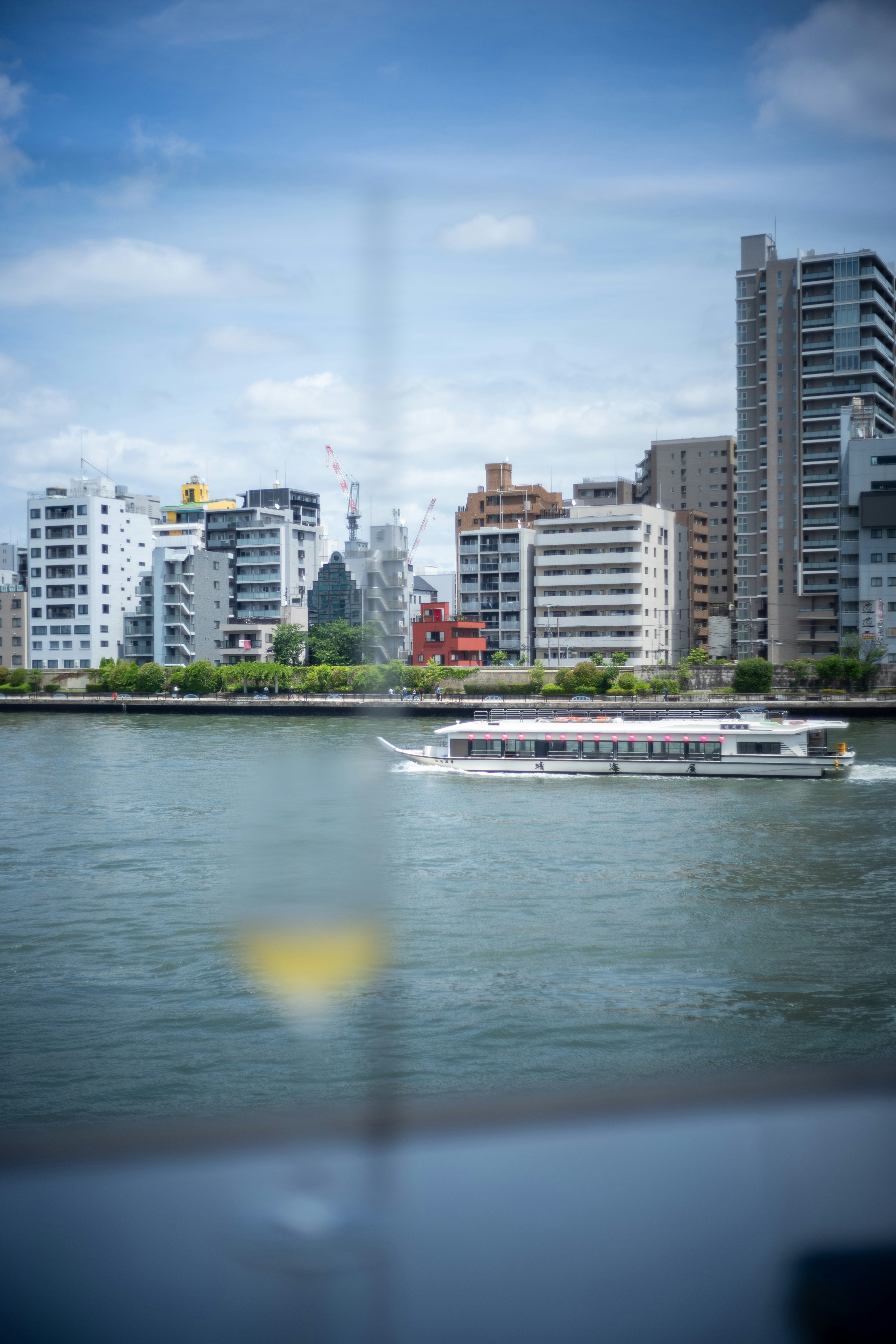 河岸高层公寓与滨水步道的城市景观，水面有船只
