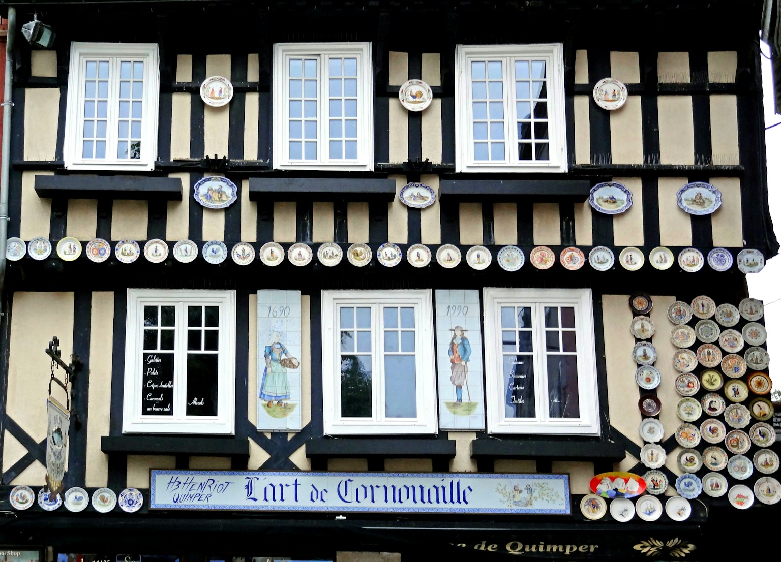 Fassade eines Fachwerkhauses mit weißen Fenstern und dekorativen Tellern