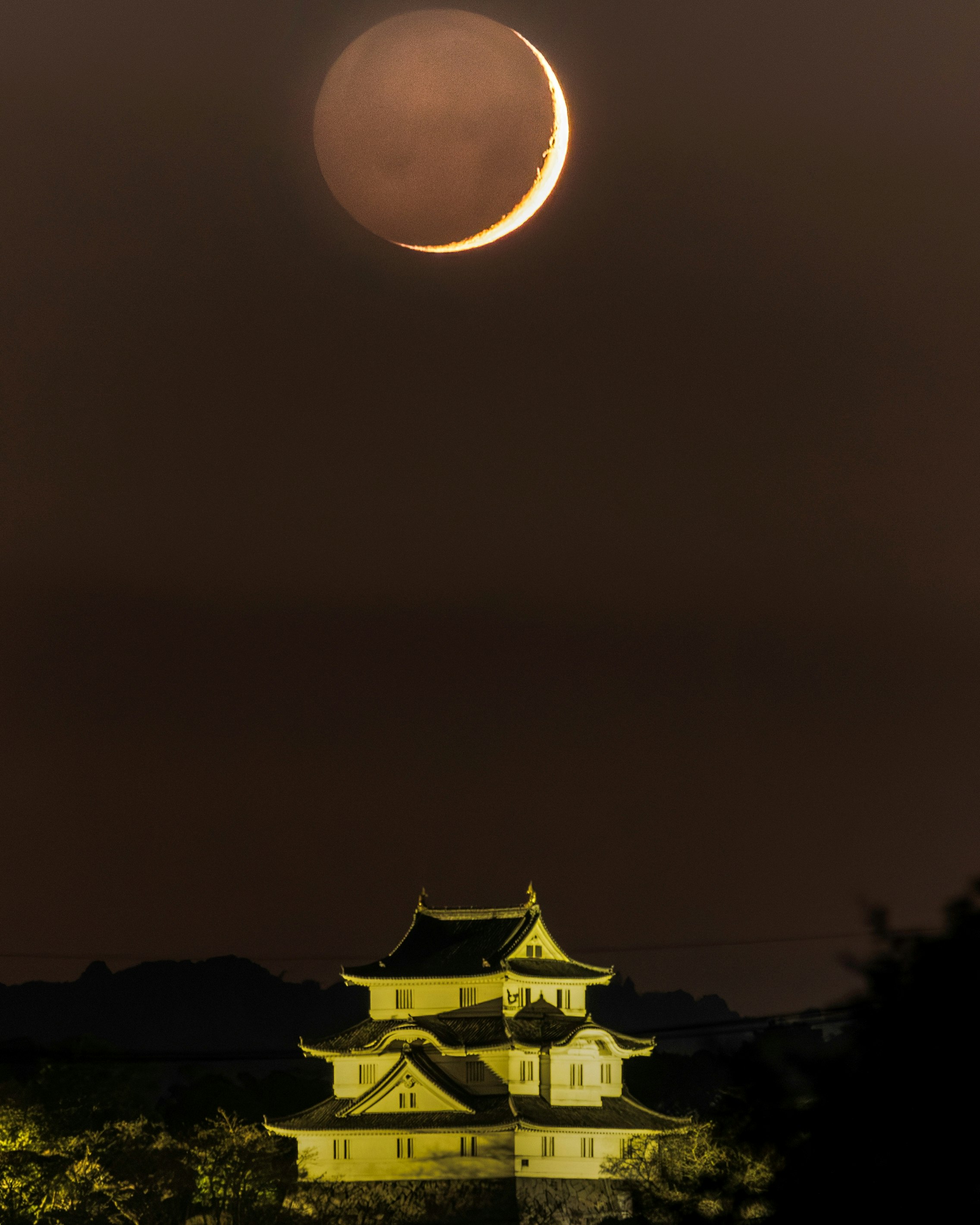 夜空に浮かぶ月と城のライトアップ