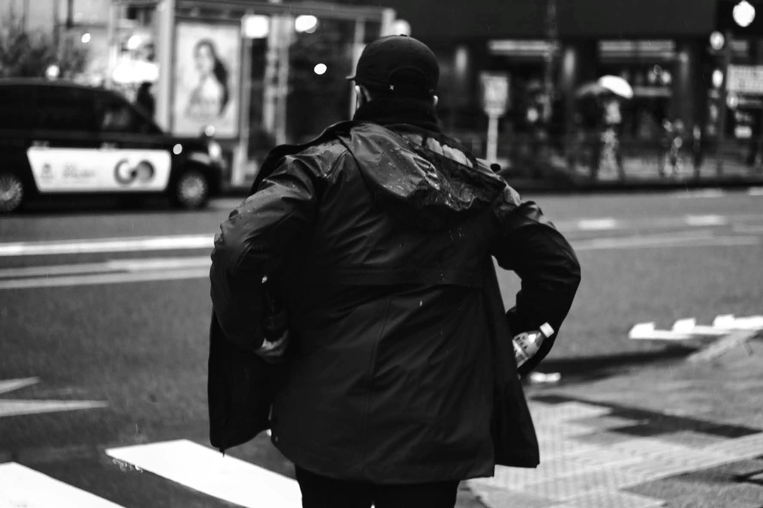 Uomo in cappotto nero che attraversa la strada in una scena cittadina