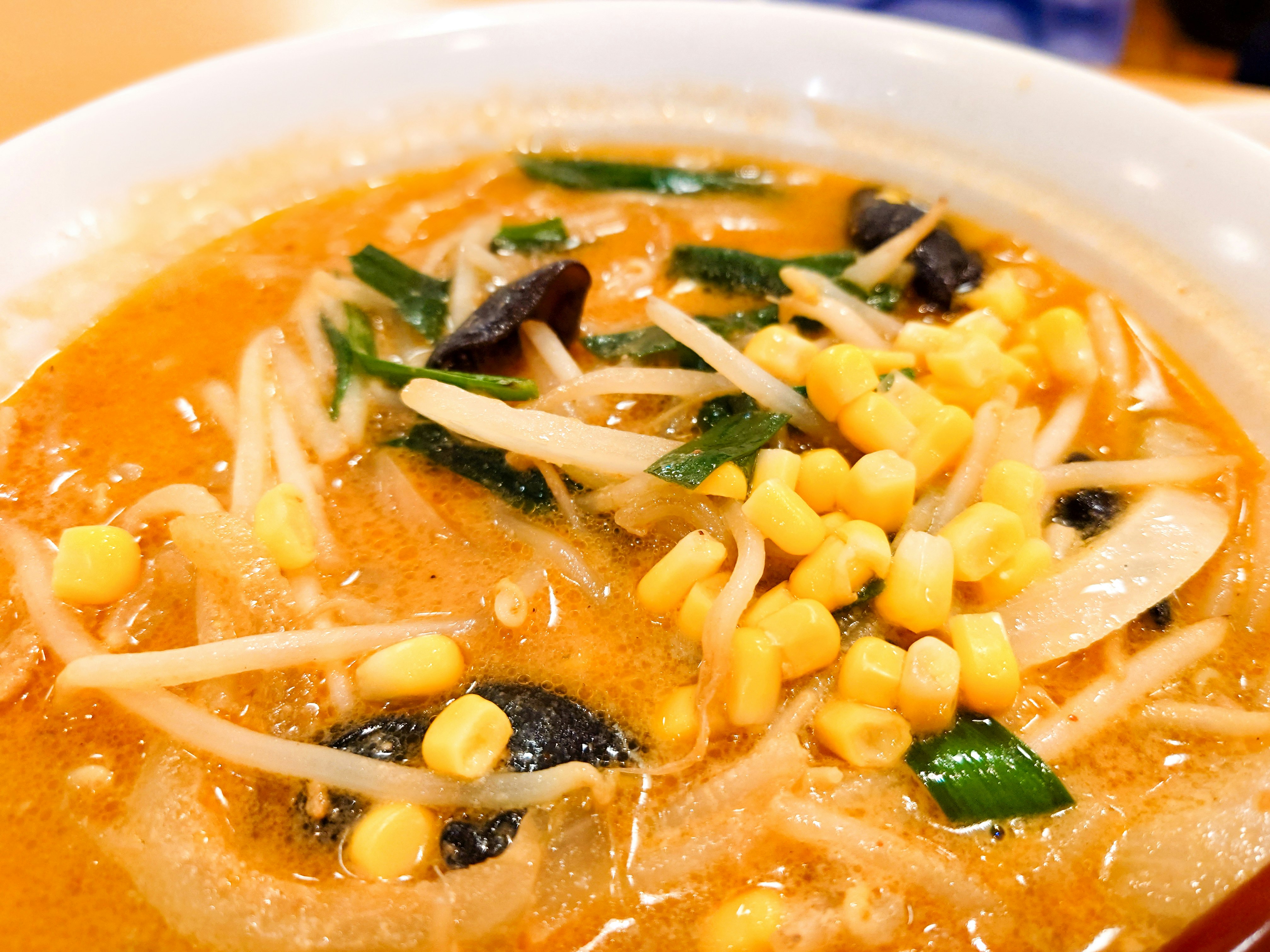 bowl of orange ramen soup with assorted toppings image