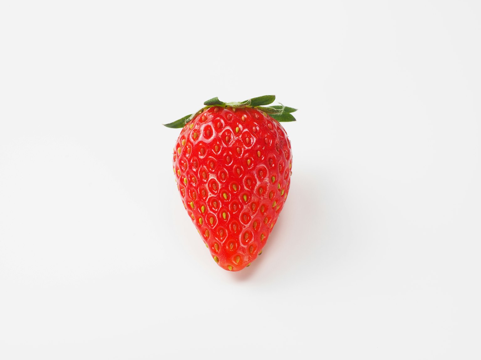 Une fraise rouge vibrante placée sur un fond blanc