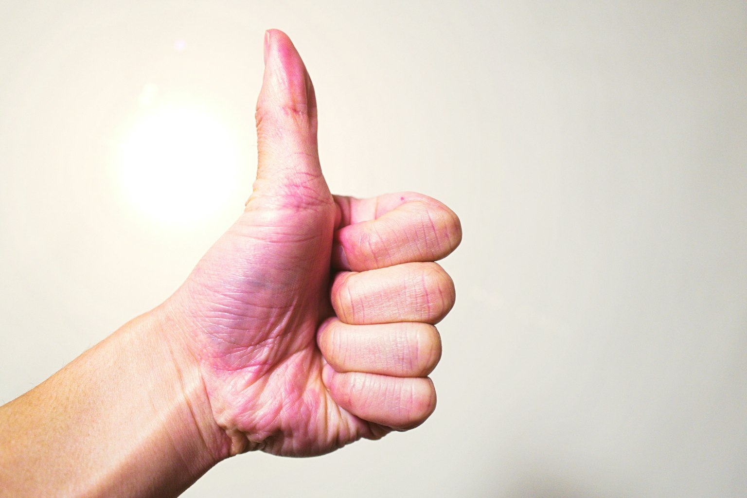 Immagine di una mano che fa un pollice in su con uno sfondo chiaro