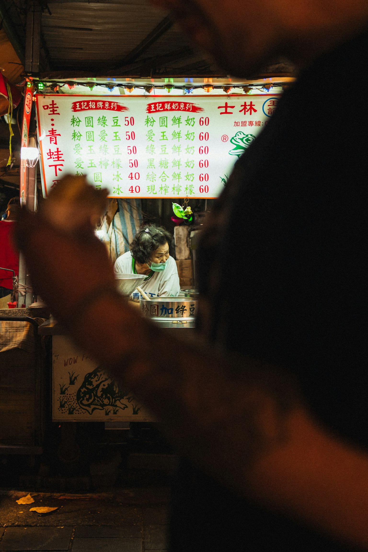 Ein Straßenverkäufer bereitet Essen vor mit einem Menü im Hintergrund