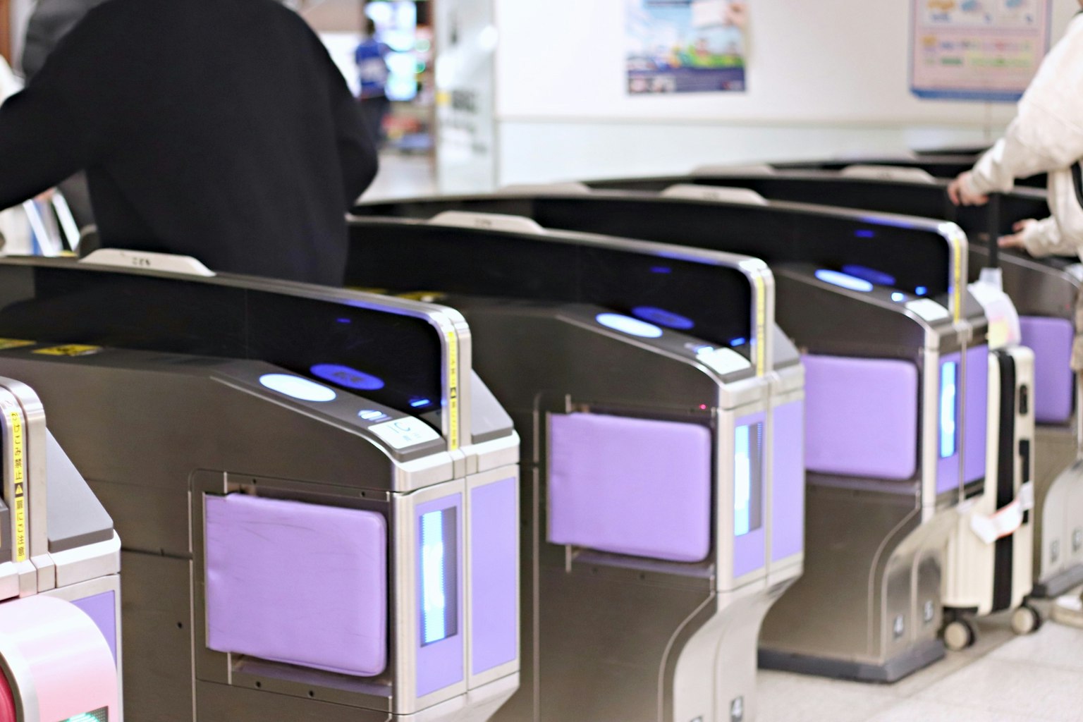 Personnes s'approchant des tourniquets automatiques avec des panneaux tactiles violets