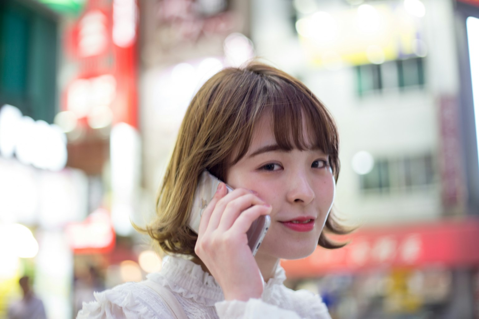 Portrait of a woman on the phone with neon signs in the background