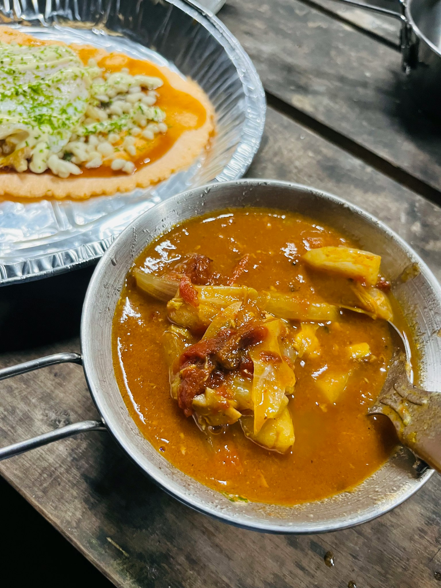 Eine Schüssel mit einem Curry-Gericht mit Fleisch- und Gemüse-Stücken neben einem Salatteller