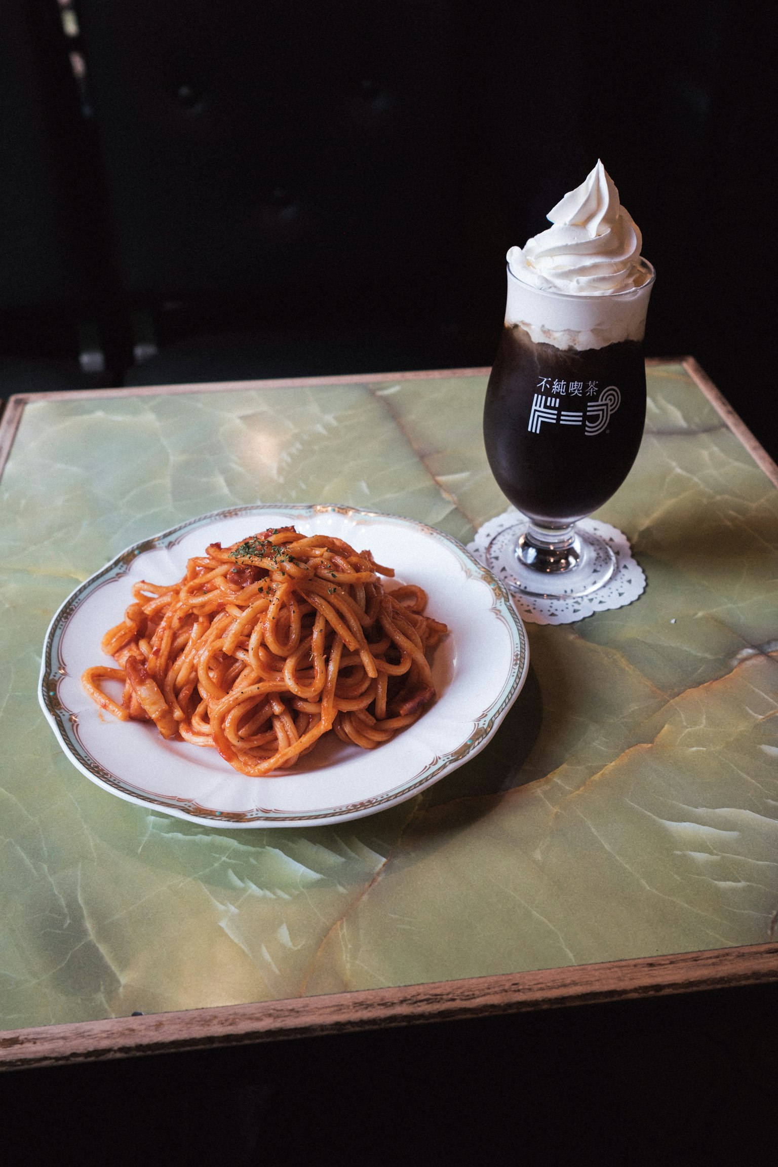 Piring spaghetti napolitan dan segelas kopi dengan krim kocok