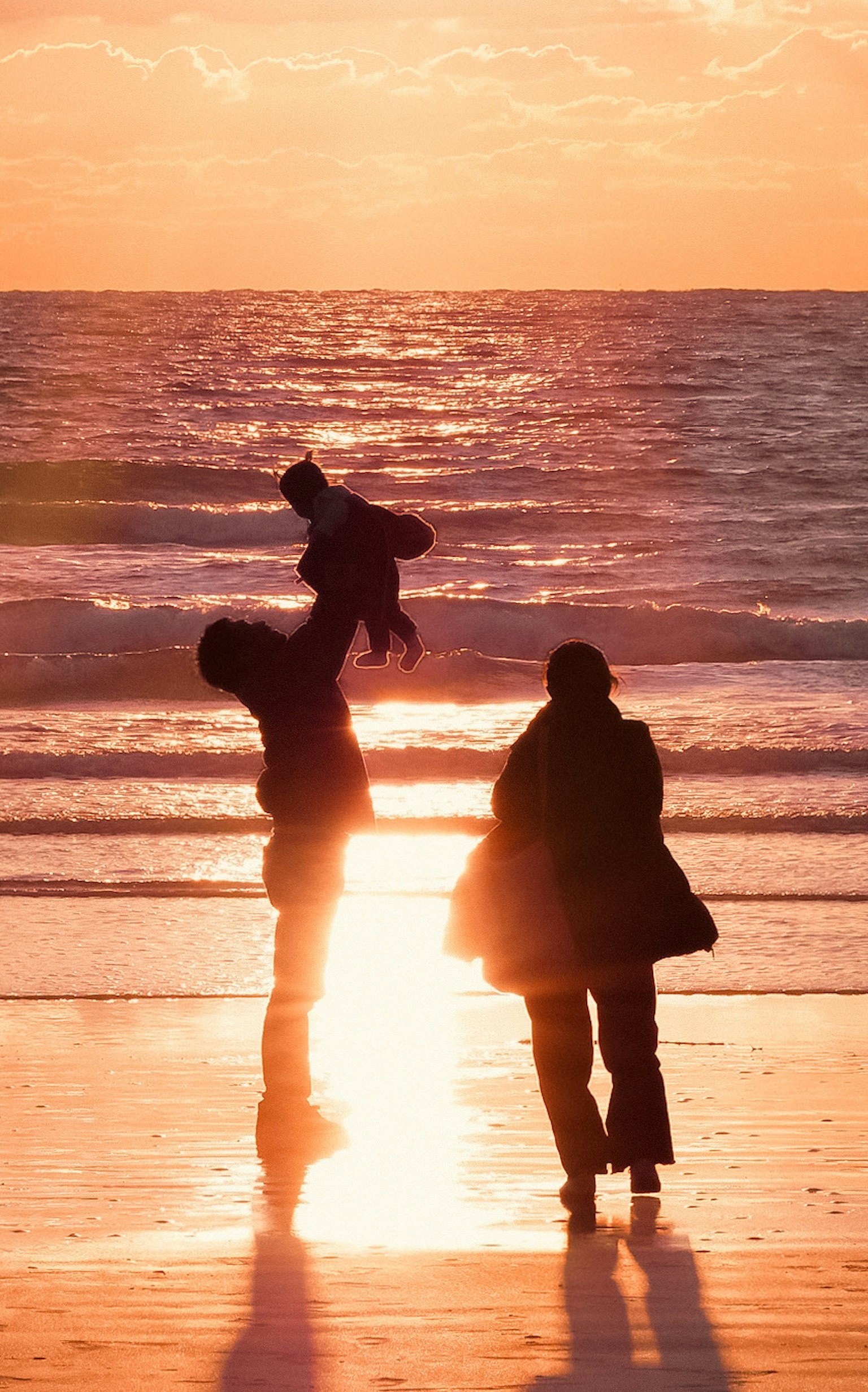 夕日を背景にした海辺での家族のシルエット