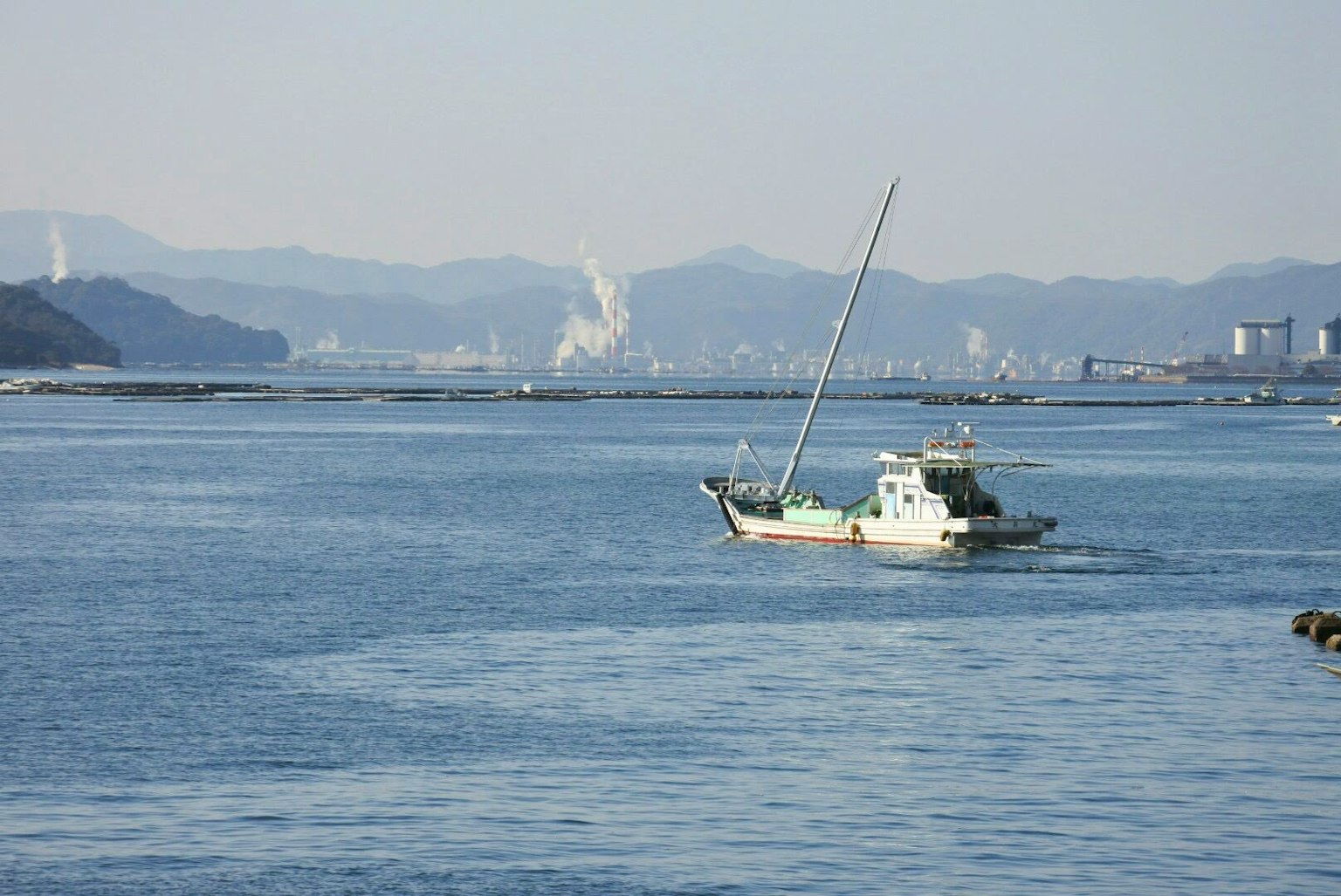Barco de pesca en un mar tranquilo con montañas distantes