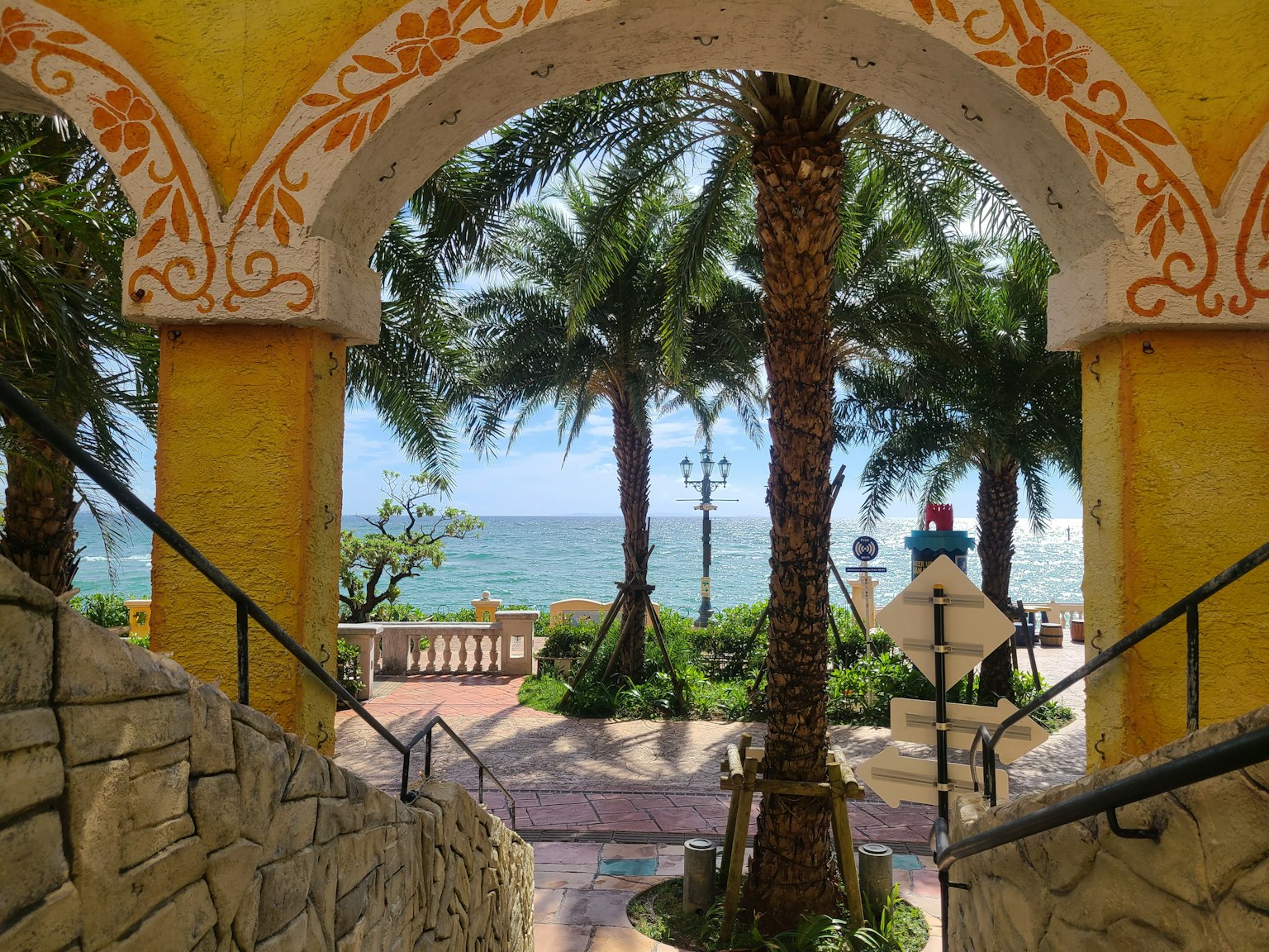 Cảnh biển và cây cọ qua cổng màu vàng