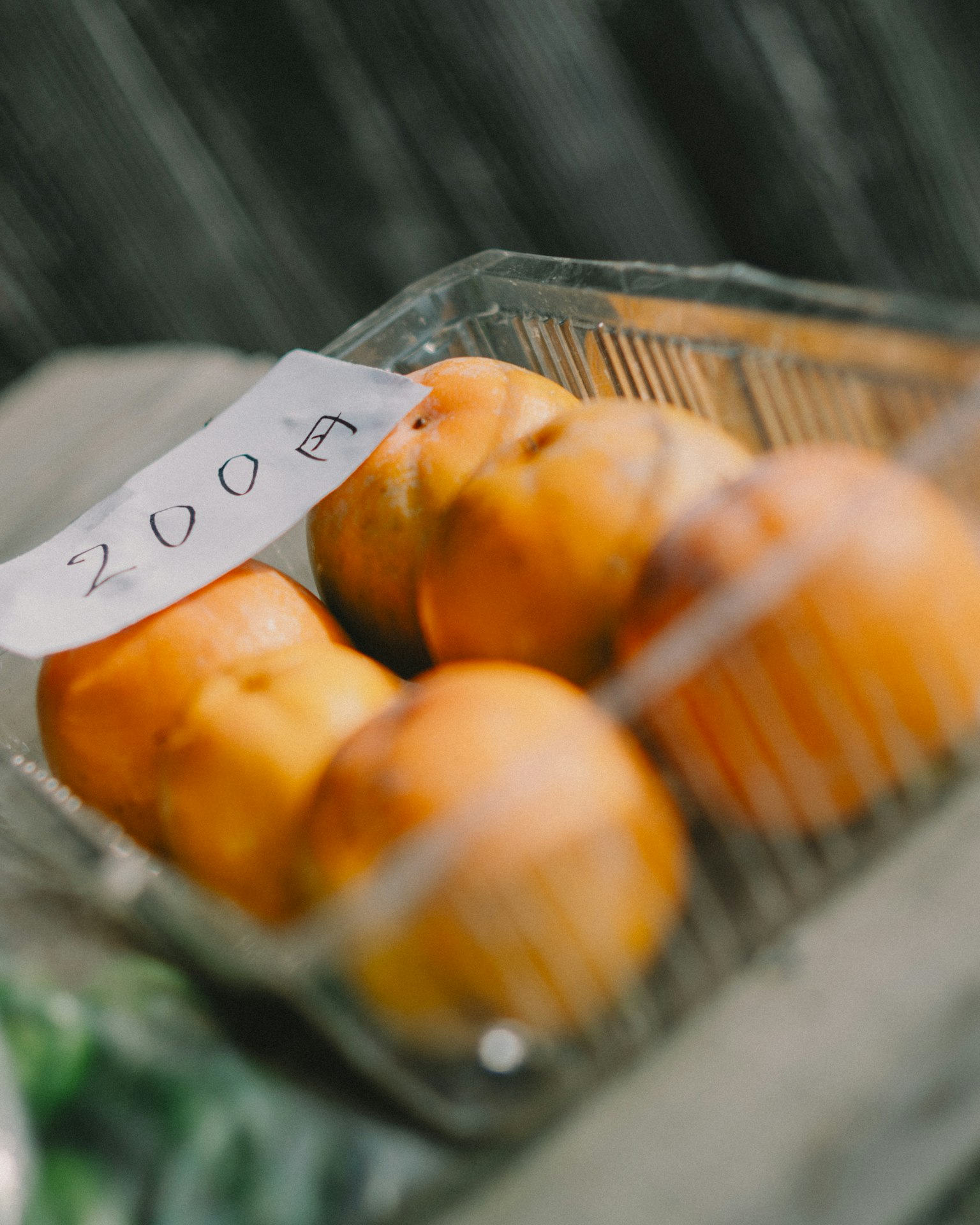 Un récipient en plastique transparent contenant des pêches orange avec le numéro 2009