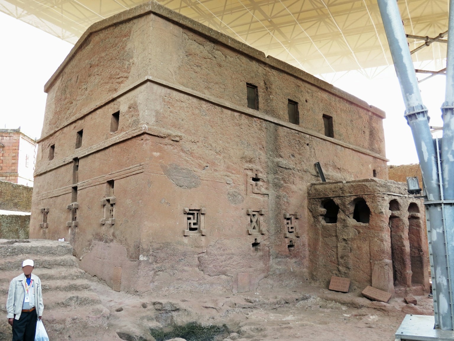 Ancient earthen structure under protective roof showcasing intricate carvings